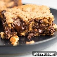 A single dark chocolate pecan cookie bar on a white plate, highlighting its rich, fudgy texture and visible pecan pieces. These gluten-free bars are incredibly delicious.