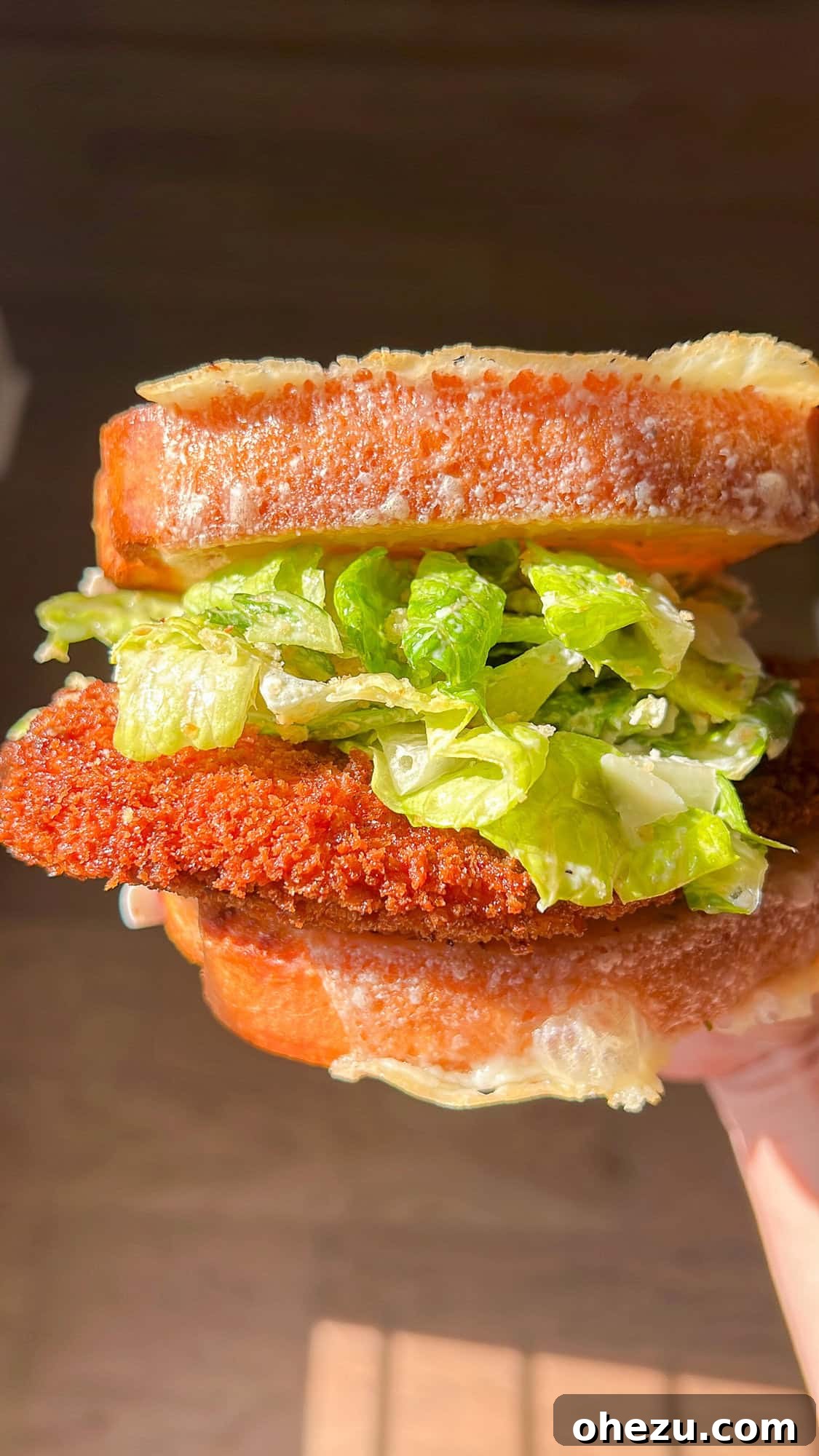 Assembling a crispy chicken Caesar salad sandwich
