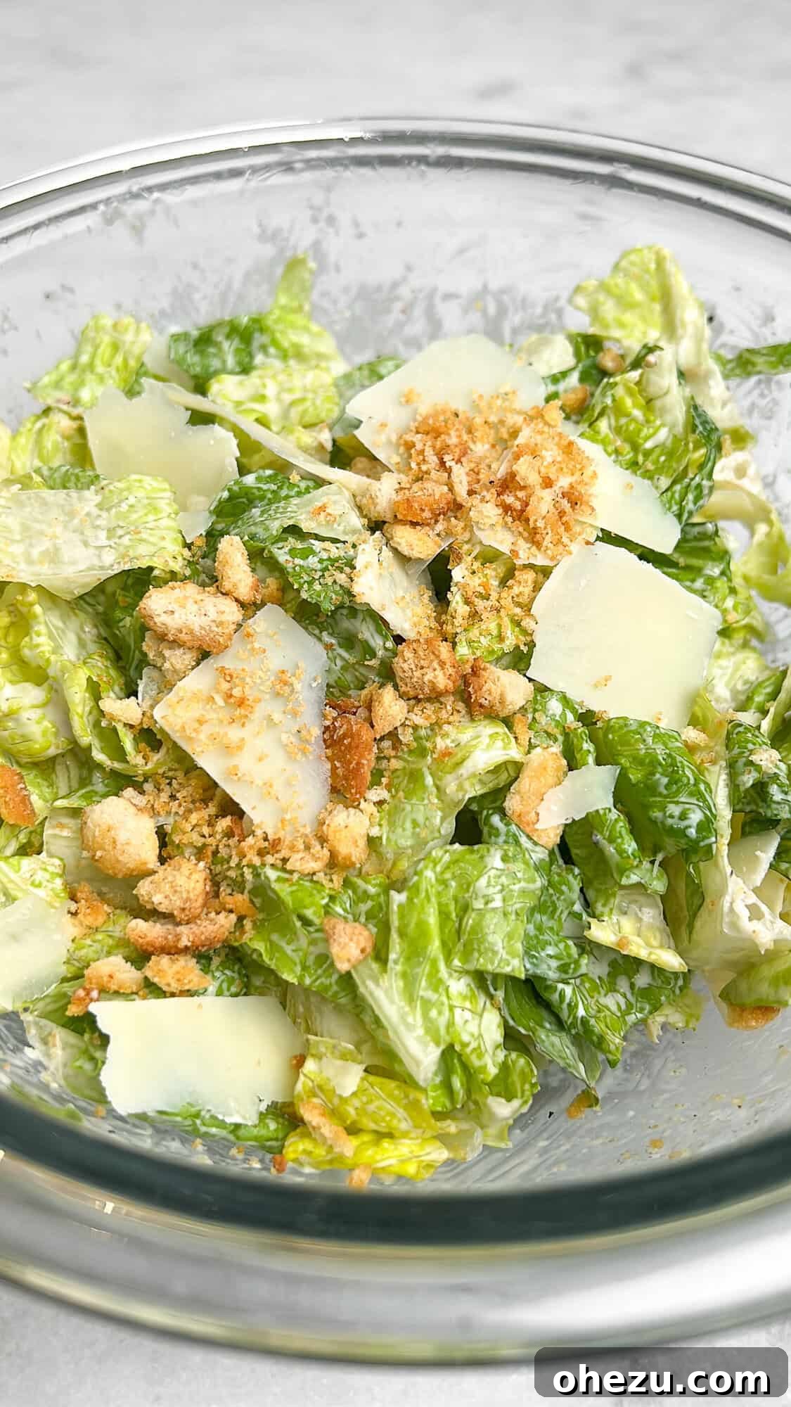 Romaine lettuce and croutons being tossed with Caesar dressing
