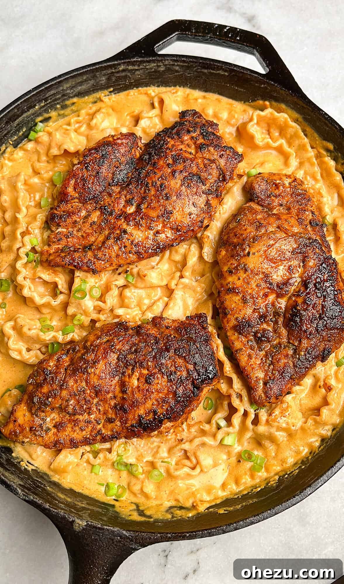 Close-up shot of the creamy buffalo chicken alfredo in a skillet, showcasing the pasta and chicken