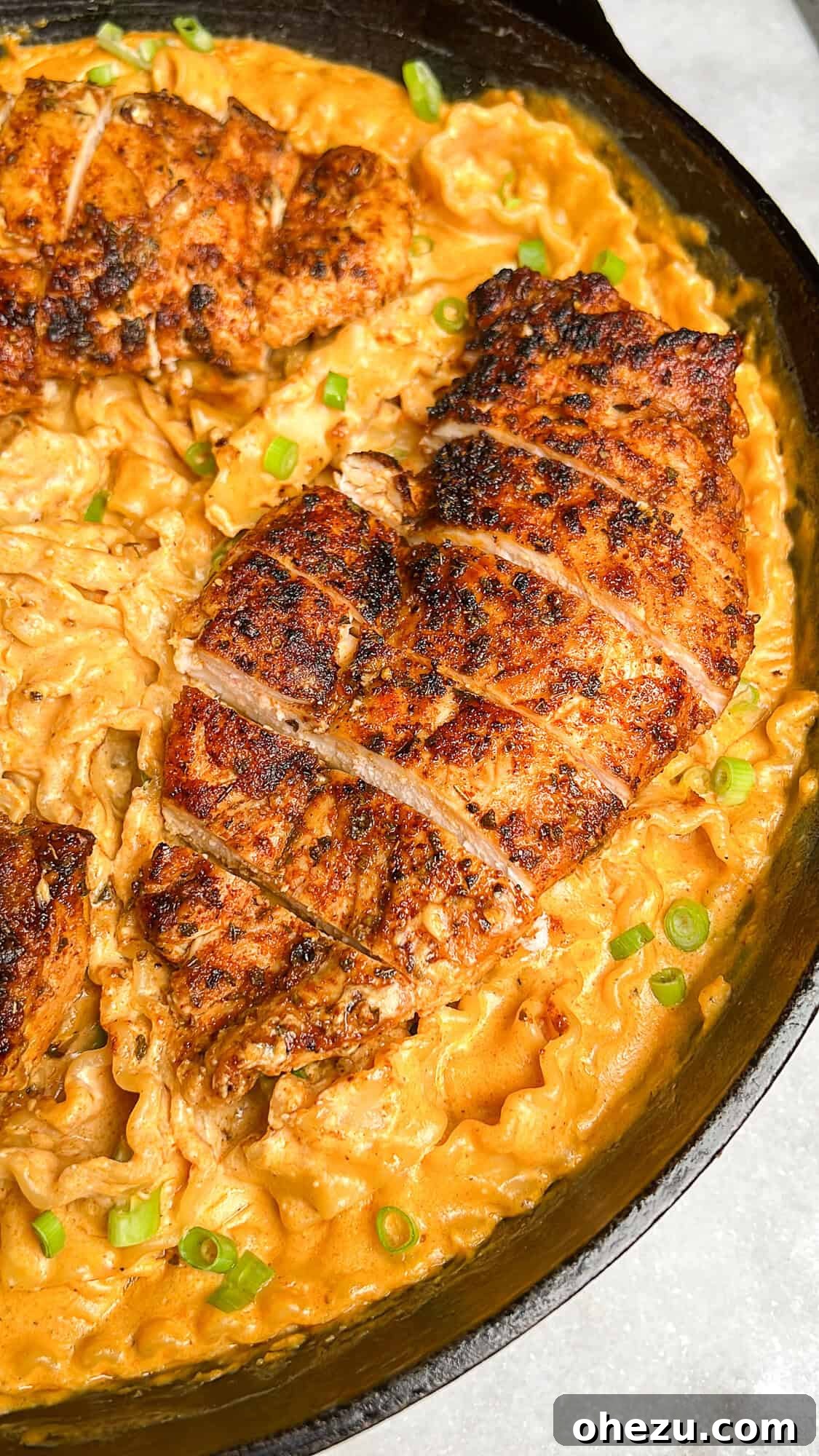 The final dish of creamy buffalo chicken alfredo, topped with sliced chicken and fresh green onions
