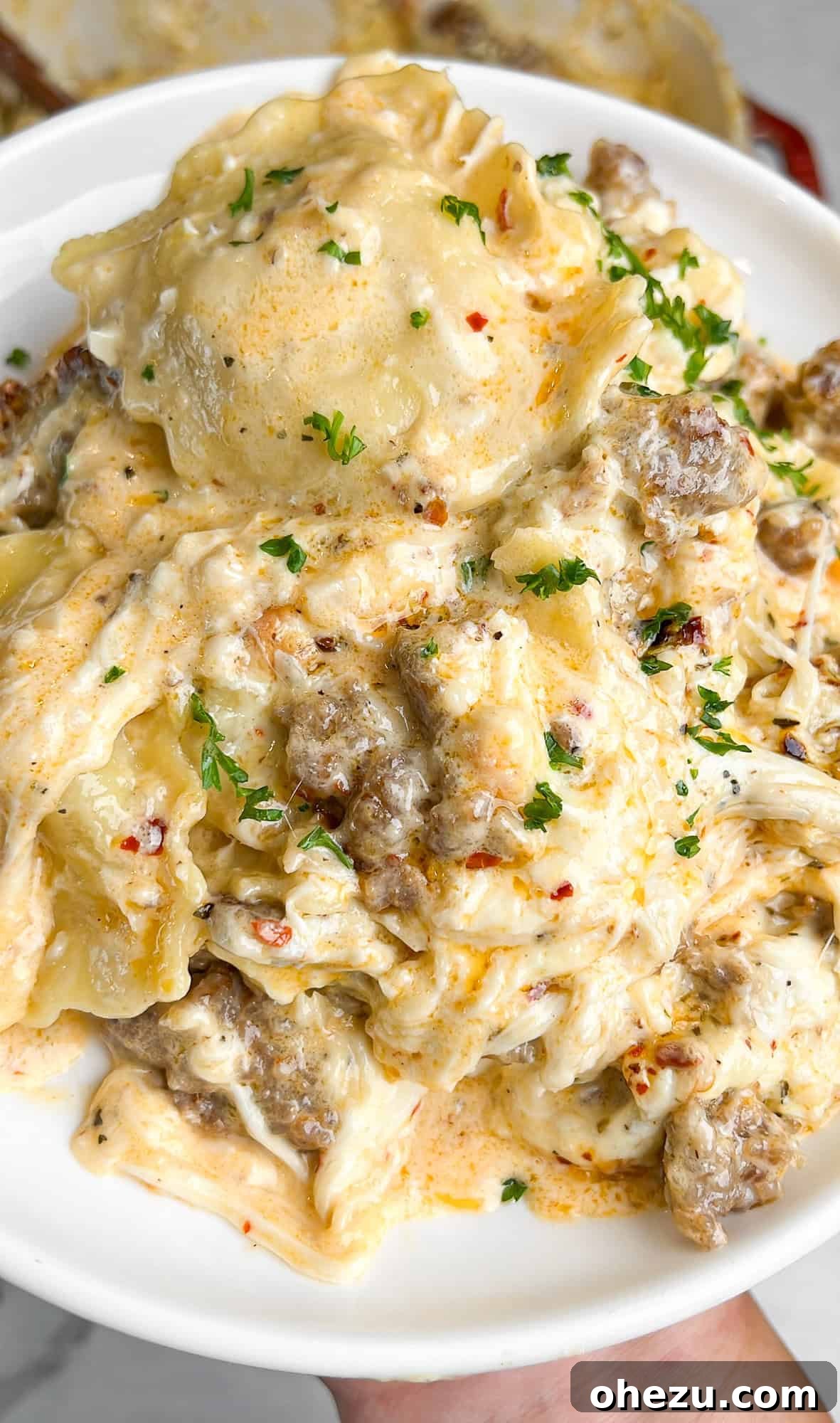 Close-up of a bubbling, cheesy Alfredo Ravioli Lasagna fresh out of the oven, showcasing the golden-brown top and melted mozzarella.