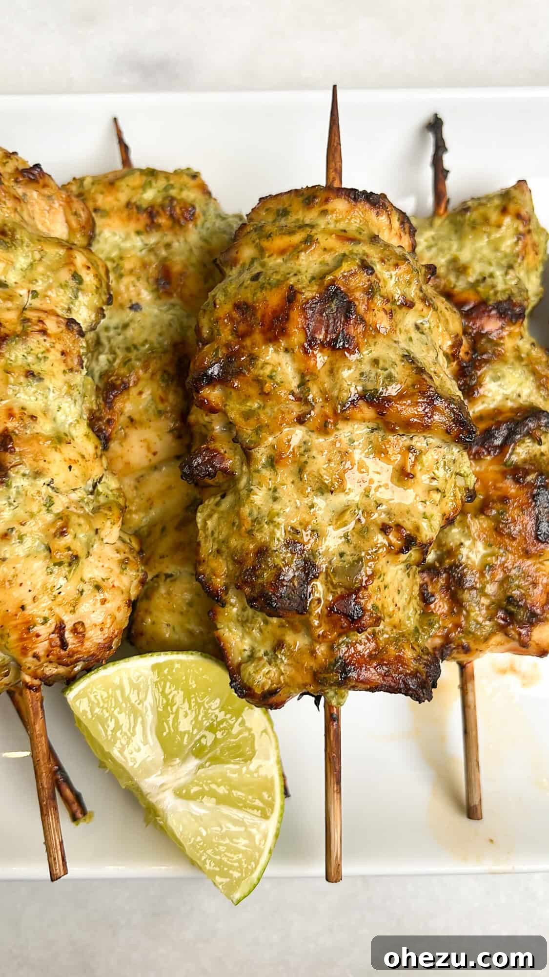 Zesty Cilantro Lime Air Fryer Chicken Skewers 10 A close-up shot of grilled chicken skewers on a plate, garnished with fresh herbs and lime.