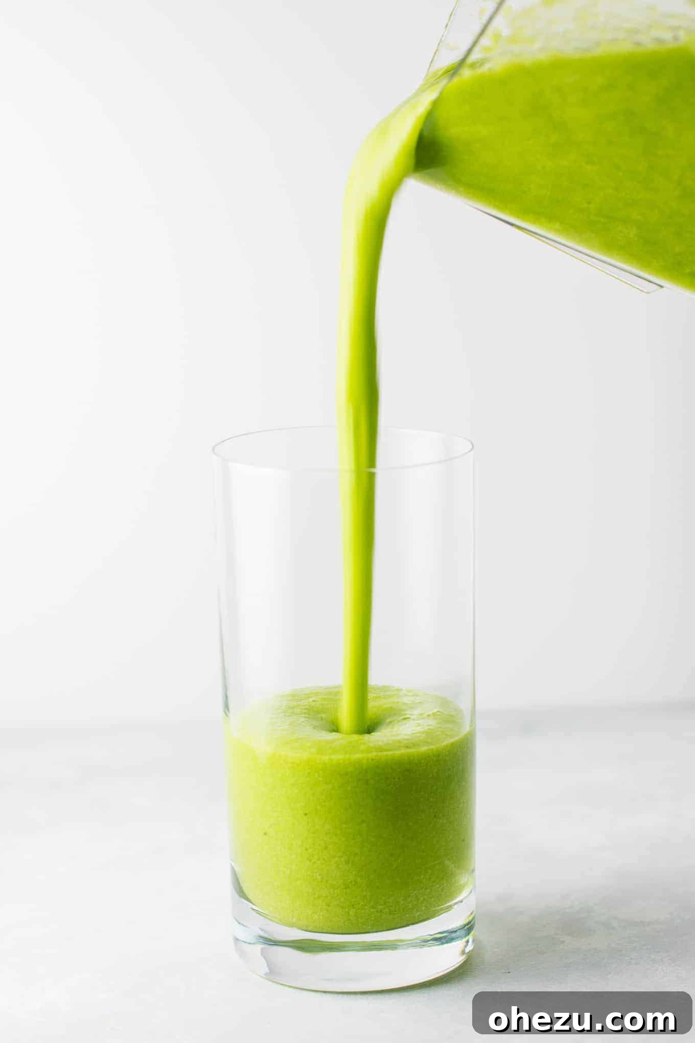 25 Must-Try Vegan Recipes for Plant-Based Perfection 12 A tall glass of the best green smoothie, vibrant green with a straw, garnished with a slice of orange.