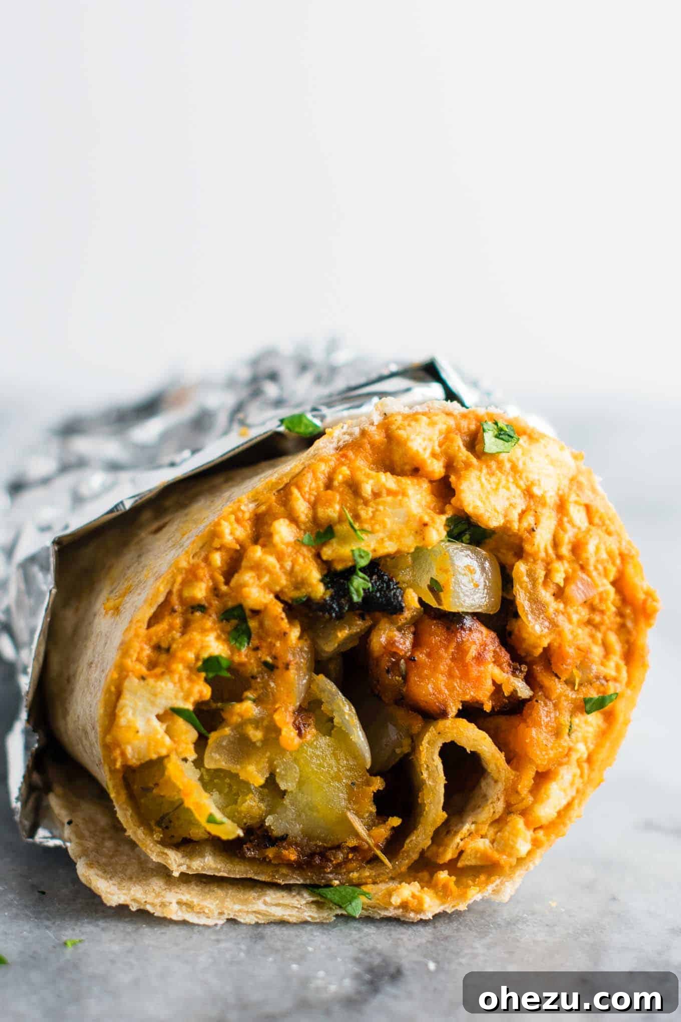 25 Must-Try Vegan Recipes for Plant-Based Perfection 3 The best vegan breakfast burrito, filled with scrambled tofu and crispy potato hash, served on parchment paper.