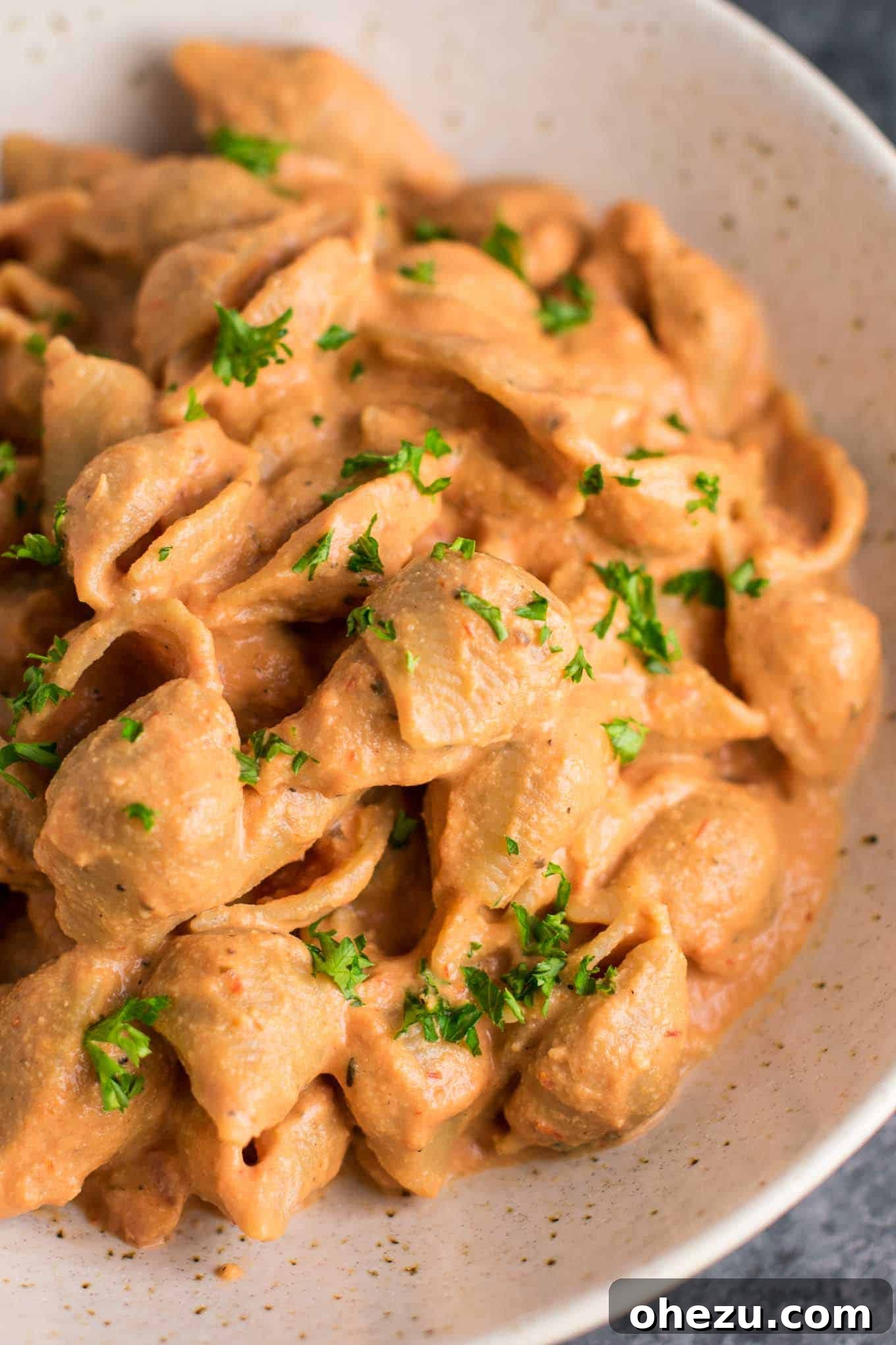 25 Must-Try Vegan Recipes for Plant-Based Perfection 22 Vegan creamy tomato shells in a large white bowl, showing pasta shells coated in a rich, pinkish sauce, garnished with fresh basil.