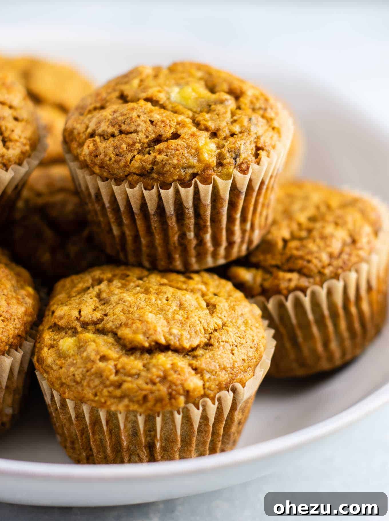 25 Must-Try Vegan Recipes for Plant-Based Perfection 8 A stack of golden-brown vegan banana muffins, showing a soft, moist interior, with fresh bananas in the background.