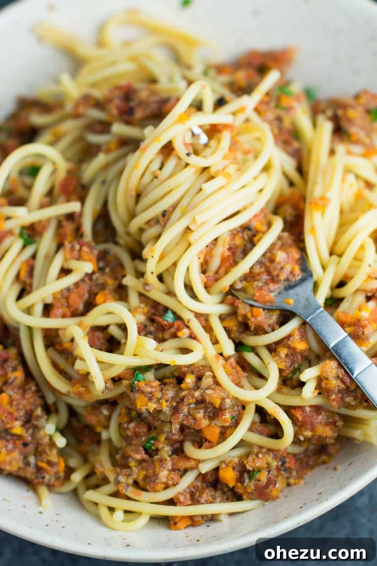 25 Must-Try Vegan Recipes for Plant-Based Perfection 9 A bowl of rich vegetable bolognese sauce with pasta, garnished with fresh herbs, showcasing its thick, meaty texture.