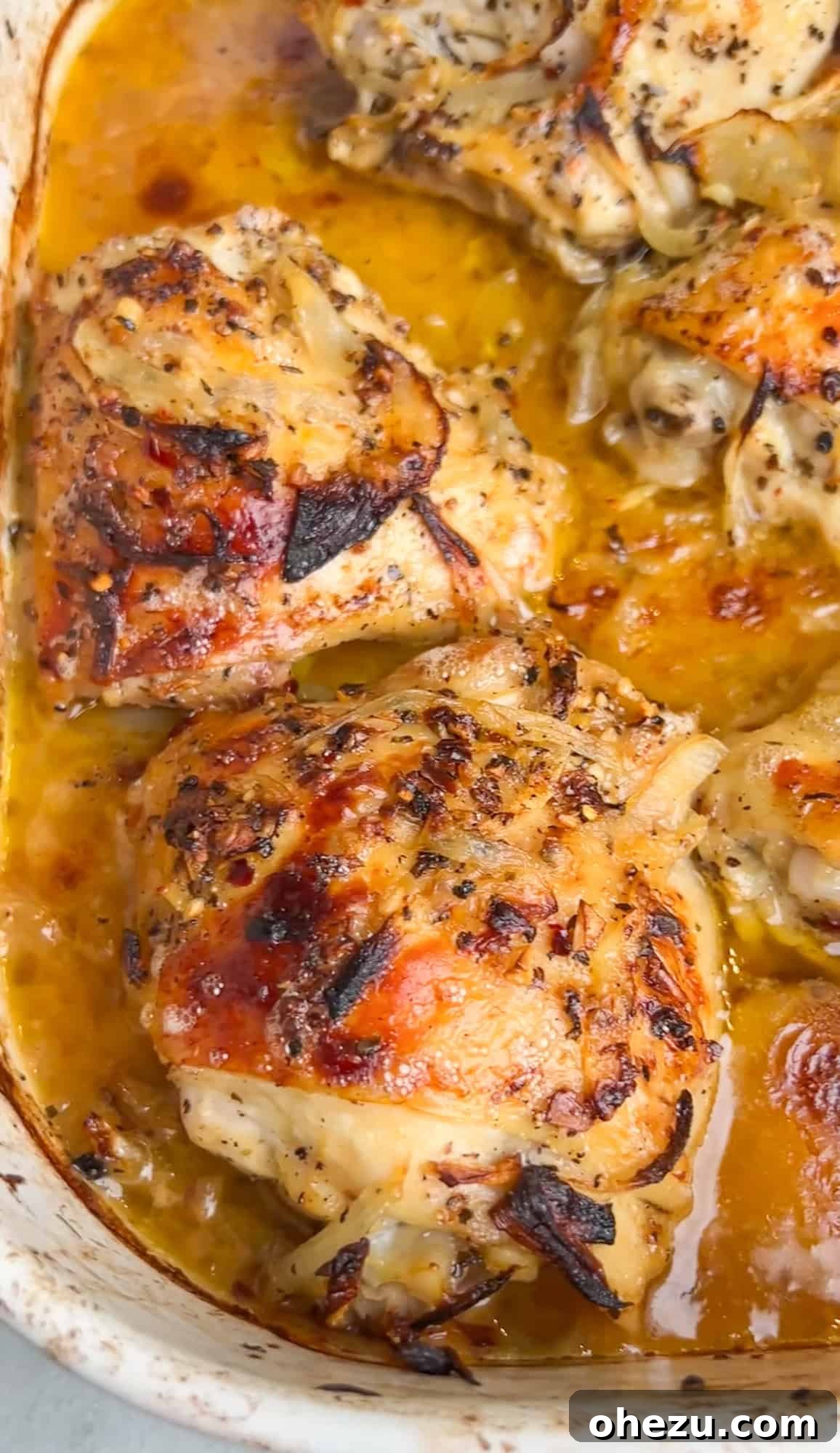 Perfectly baked chicken thighs in a roasting pan, golden brown and glistening with pan juices