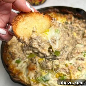 Bread being dipped into the warm, cheesy Philly Cheesesteak Dip