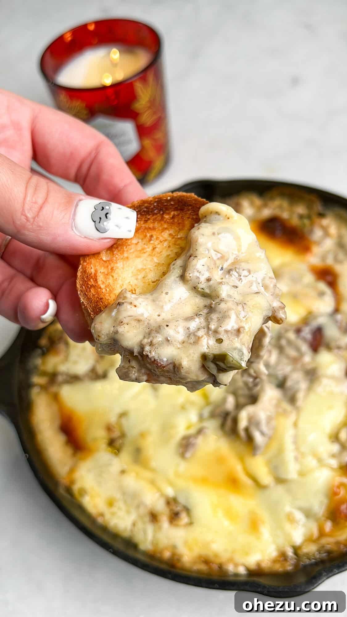 Finished Philly Cheesesteak Dip in a black cast iron skillet, golden brown and garnished