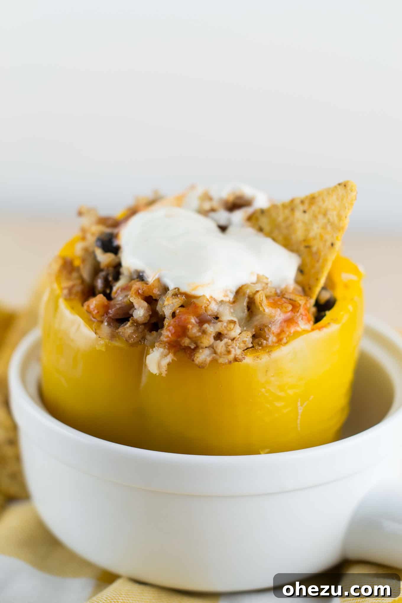 No-Fuss Slow Cooker Plant-Based Stuffed Peppers 10 A plate of two vibrant vegetarian crockpot stuffed peppers, garnished with fresh lime, sour cream, and hot sauce, served with tortilla chips.