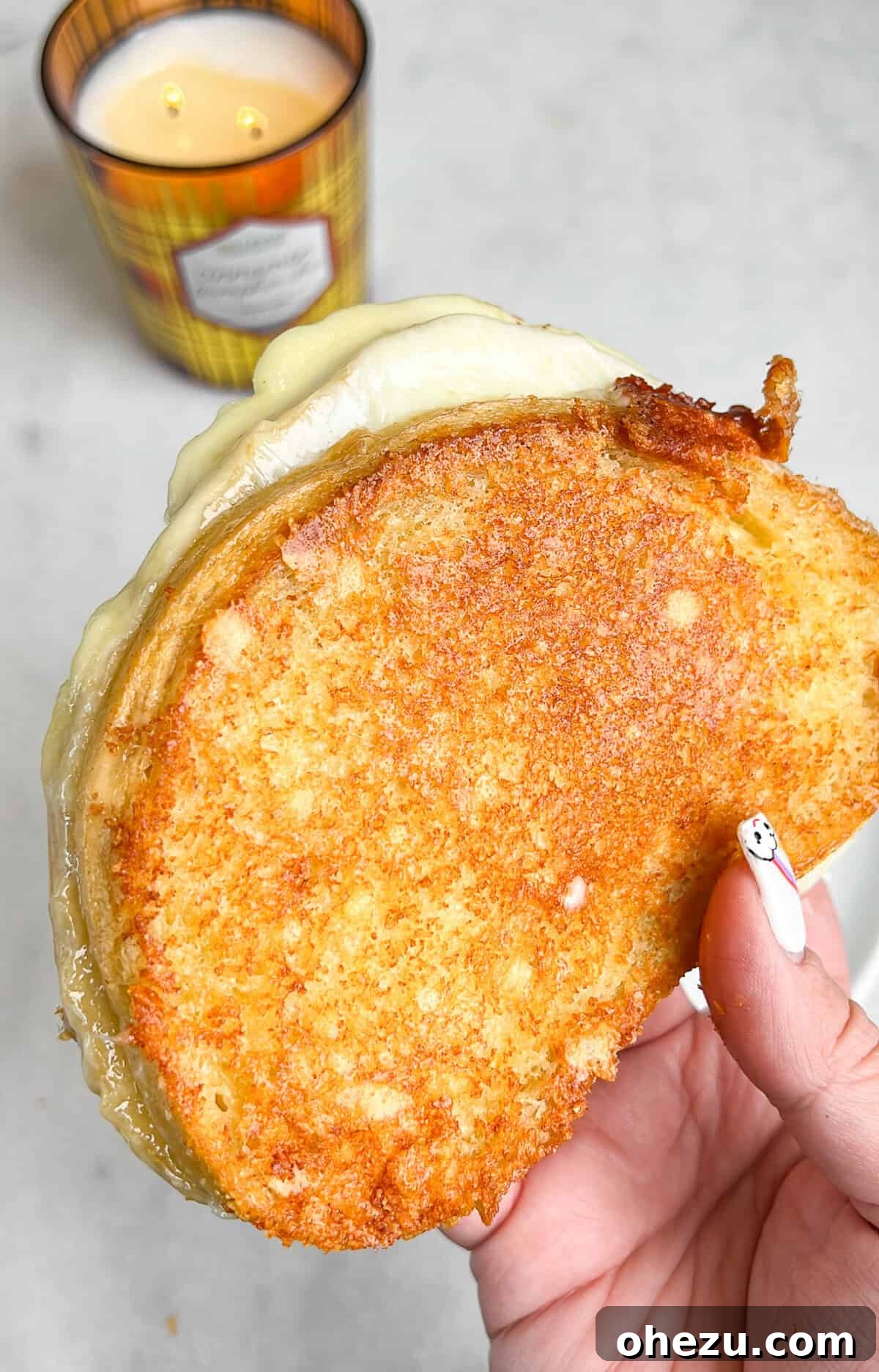 A close-up of a grilled cheese sandwich cut in half, showcasing the layers of melted cheese and toasted sourdough bread.