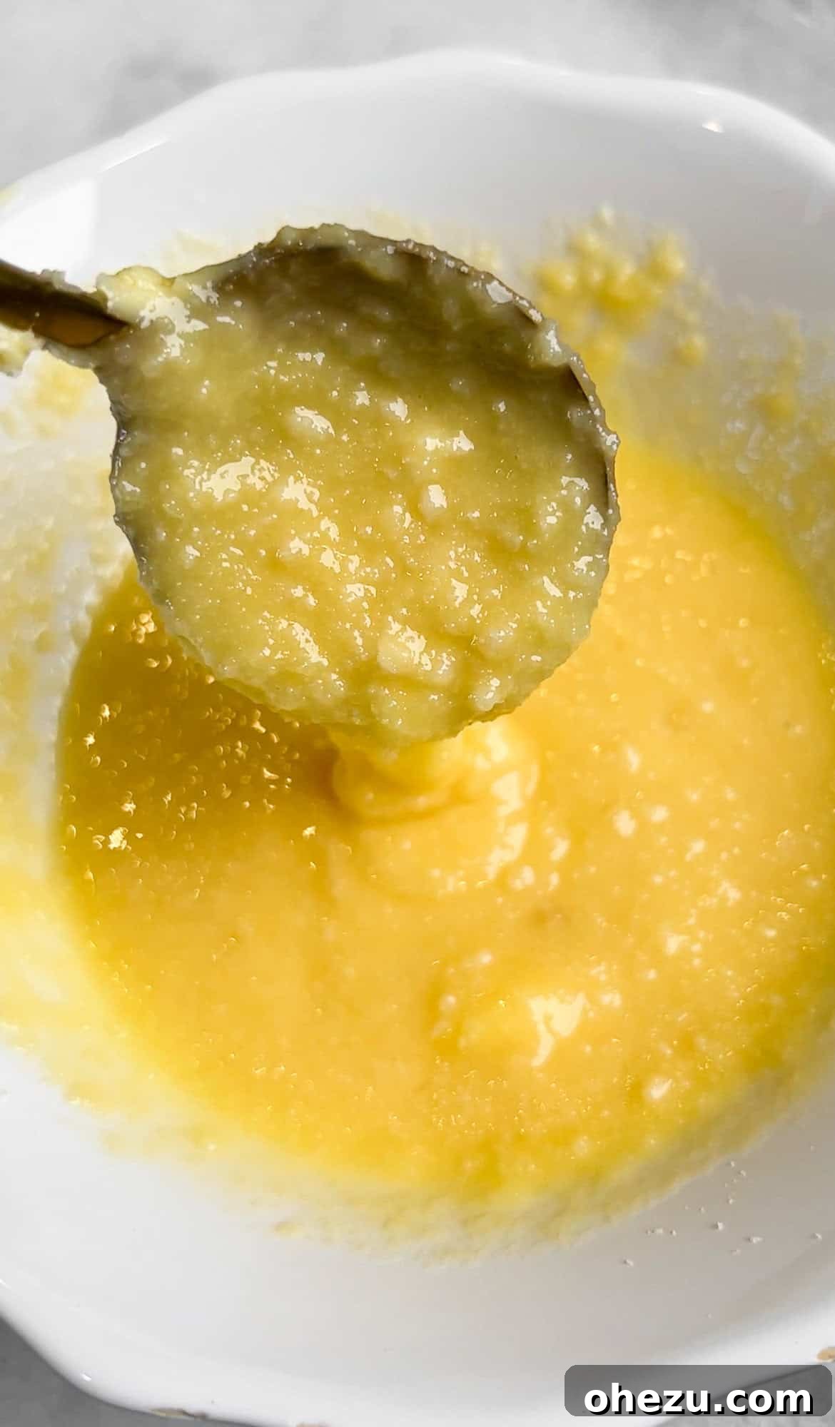 A bowl of creamy Parmesan and garlic butter spread with a mixing spoon, ready for use.