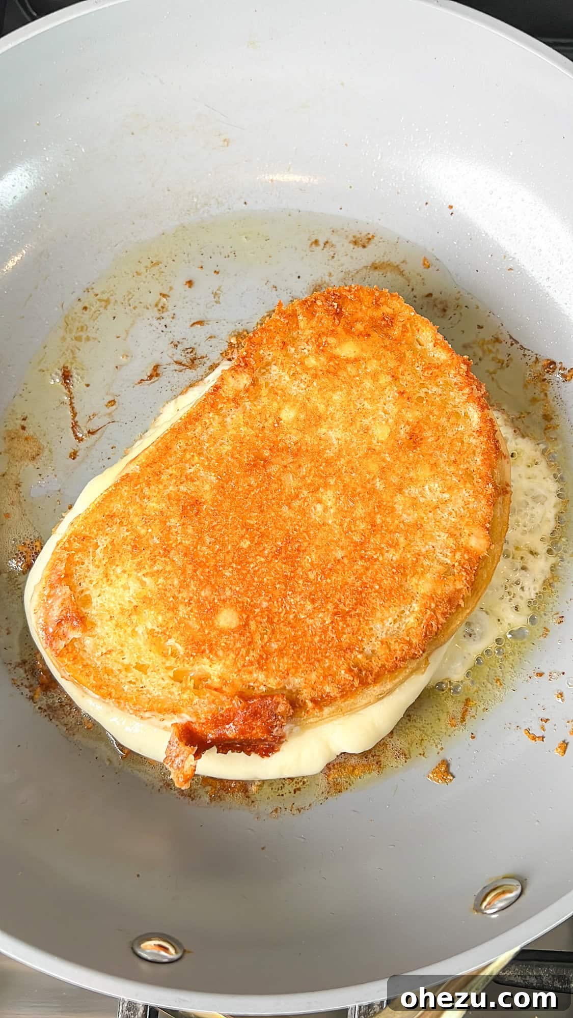 A copycat Starbucks grilled cheese sandwich sizzling in a pan, nearly ready.