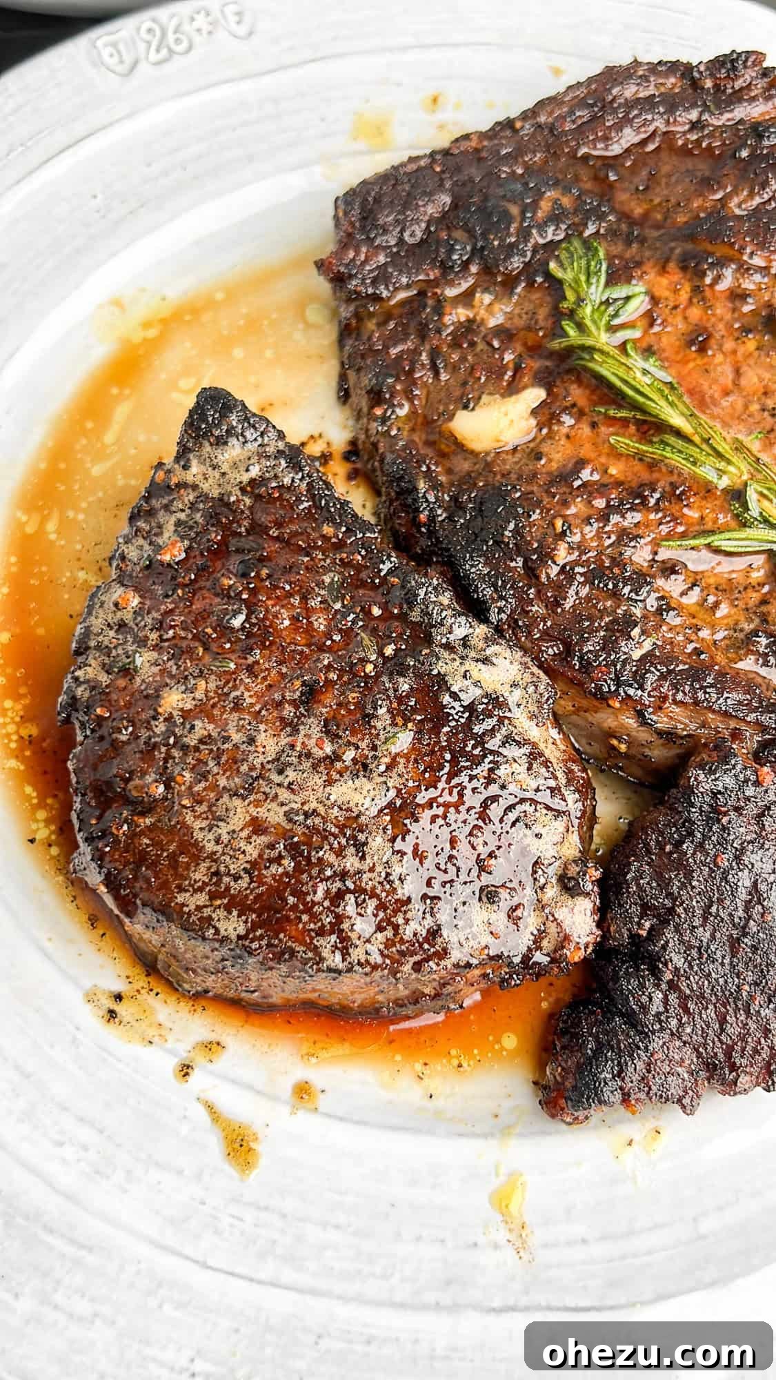 Cognac Kissed Cast Iron Steak 7 Two beautifully seared steaks resting on a white plate.
