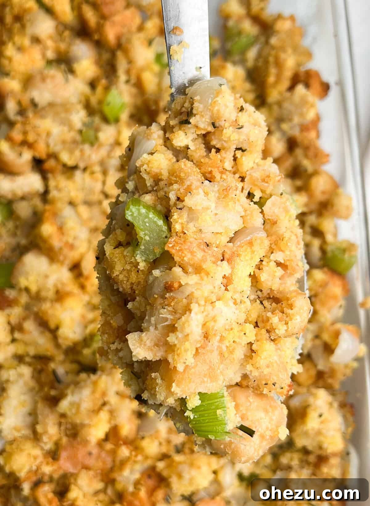 Close-up of golden brown cornbread stuffing in a baking pan, ready to be served.