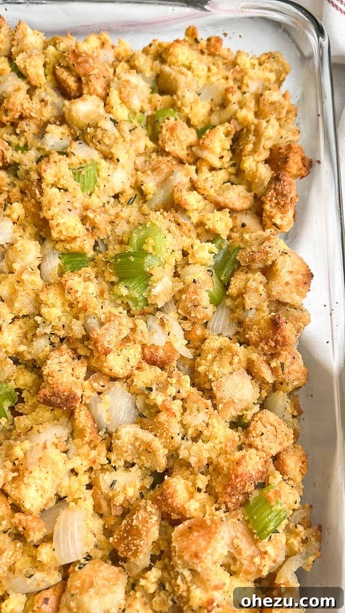 Freshly baked cornbread dressing with a golden-brown crust, served in a ceramic dish.