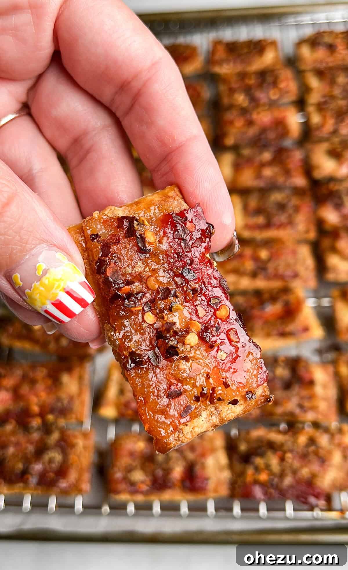 Freshly baked Boursin Candied Bacon Crackers cooling on a wire rack over a baking sheet, ready to be served.