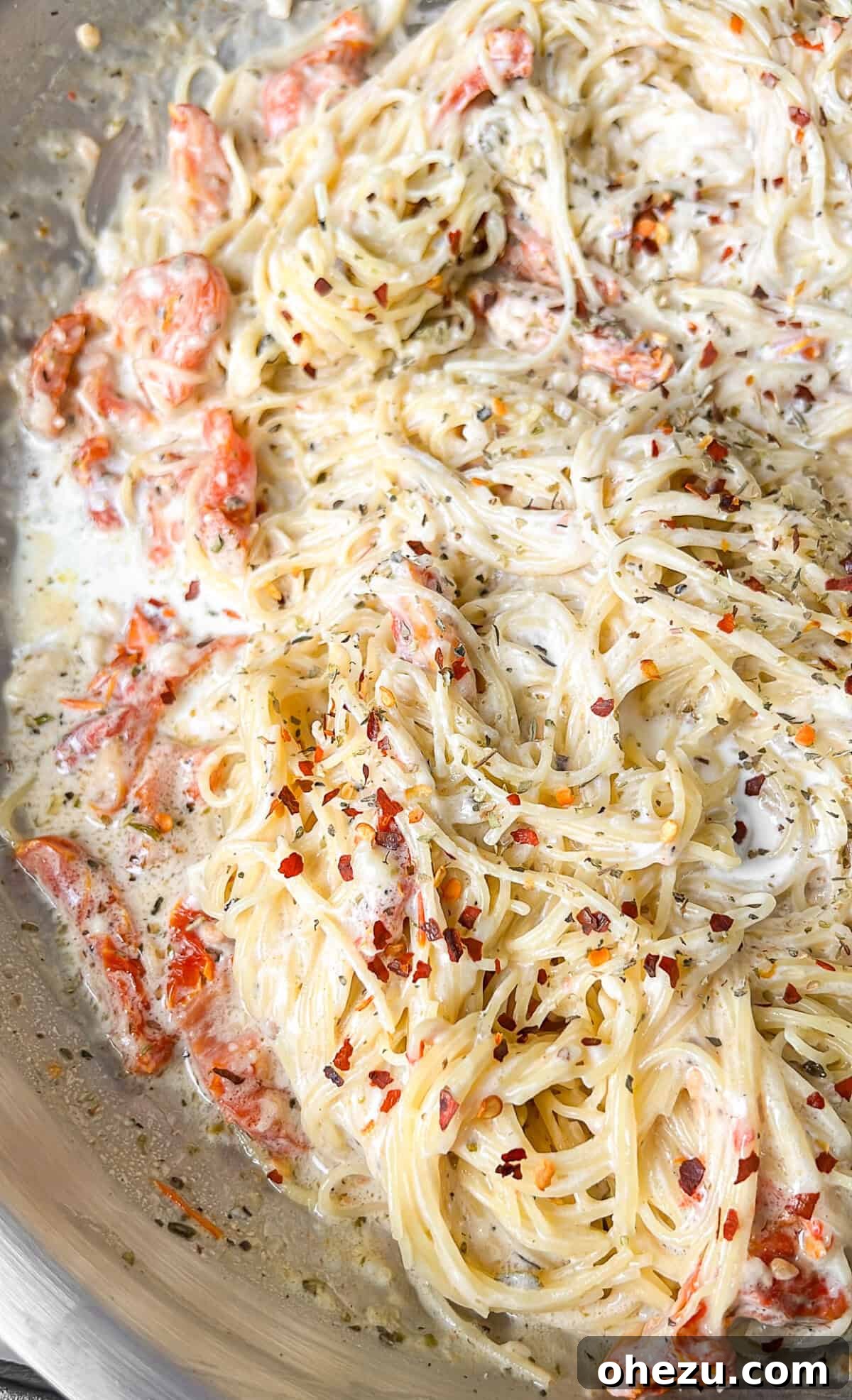 Effortless Skillet Sun Dried Tomato Pasta 3 A serving of creamy sun-dried tomato pasta in a bowl, with a fork twirled in it, suggesting a delicious bite.
