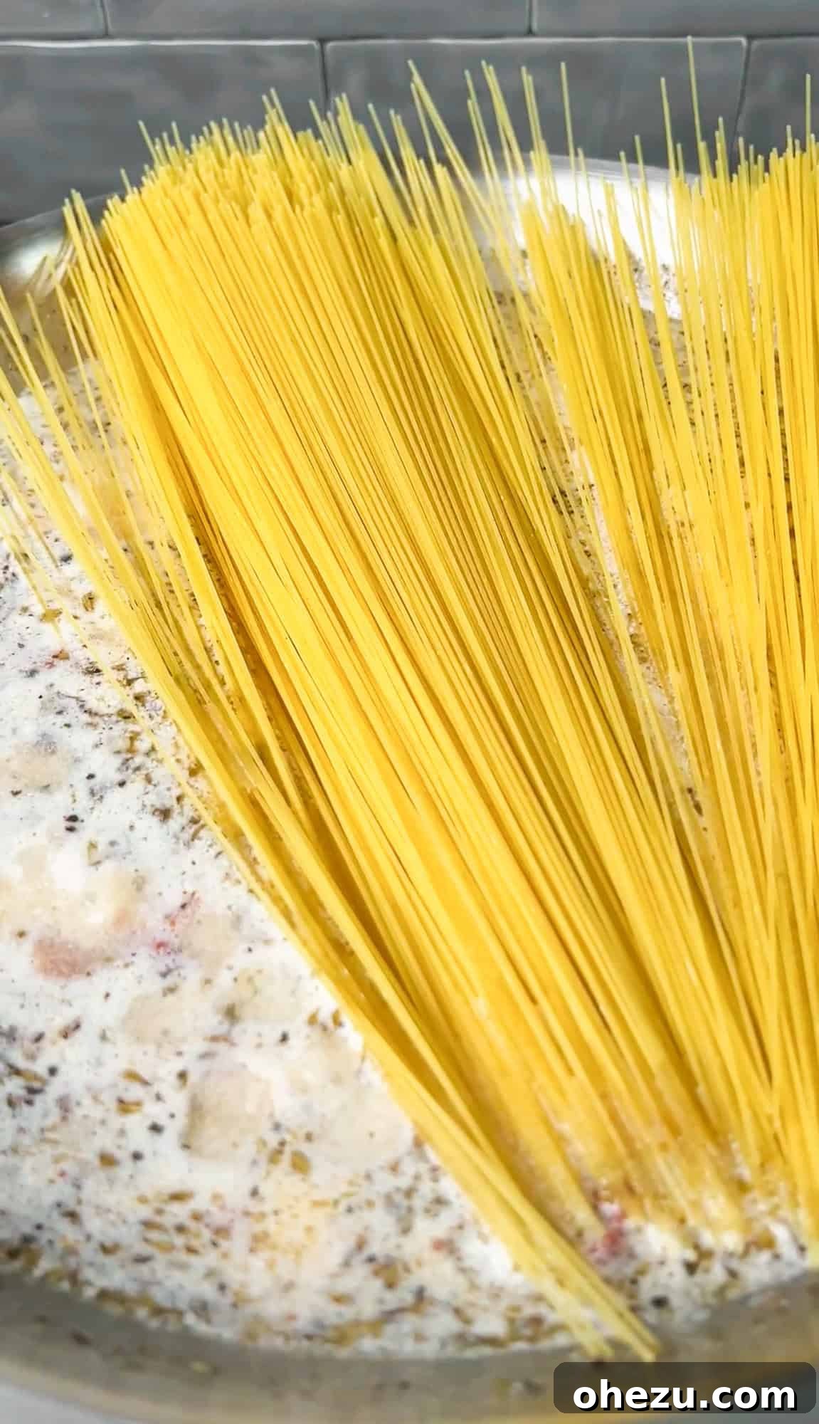 Effortless Skillet Sun Dried Tomato Pasta 5 Angel hair pasta being gently pushed into the simmering sauce in a pan.