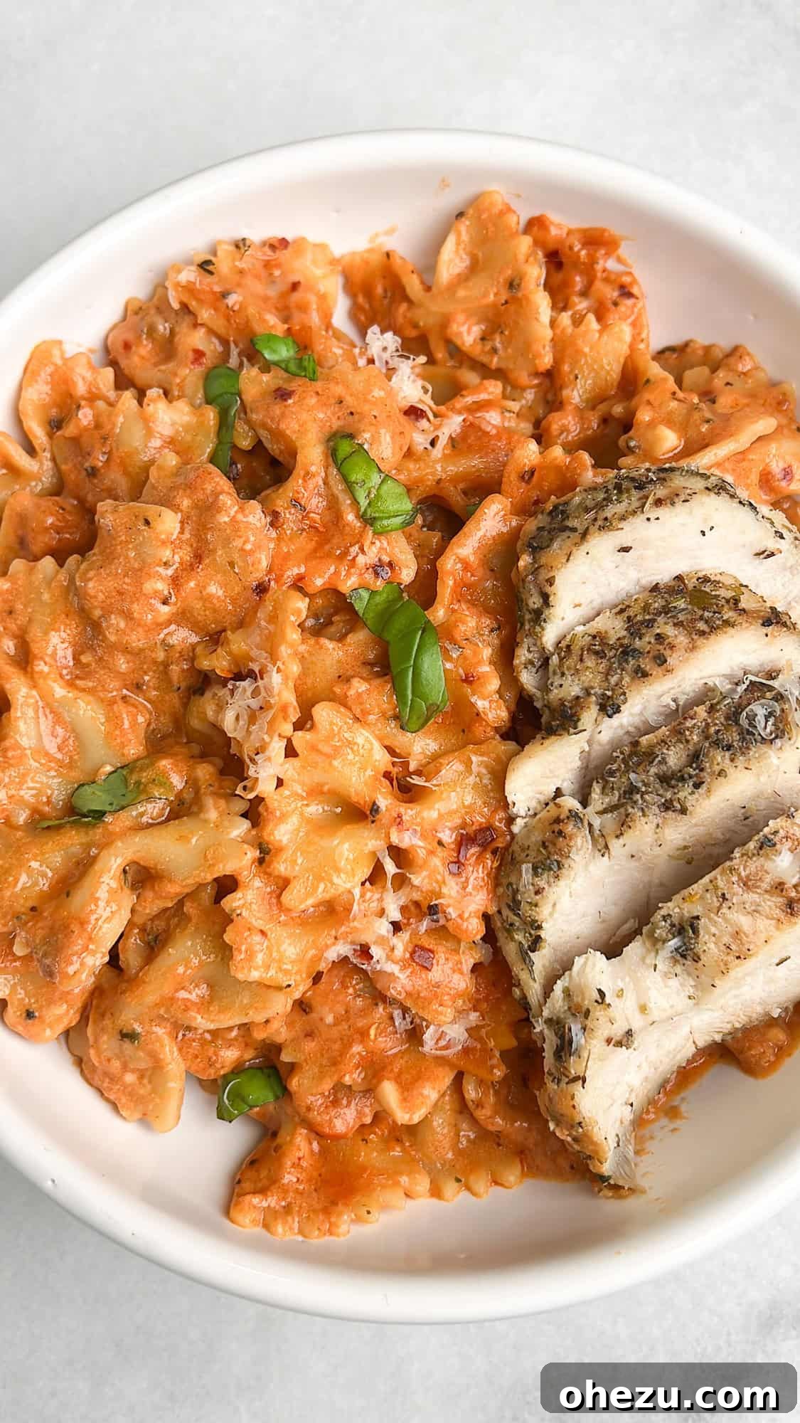 Rose pink pasta with chicken, garnished with fresh basil