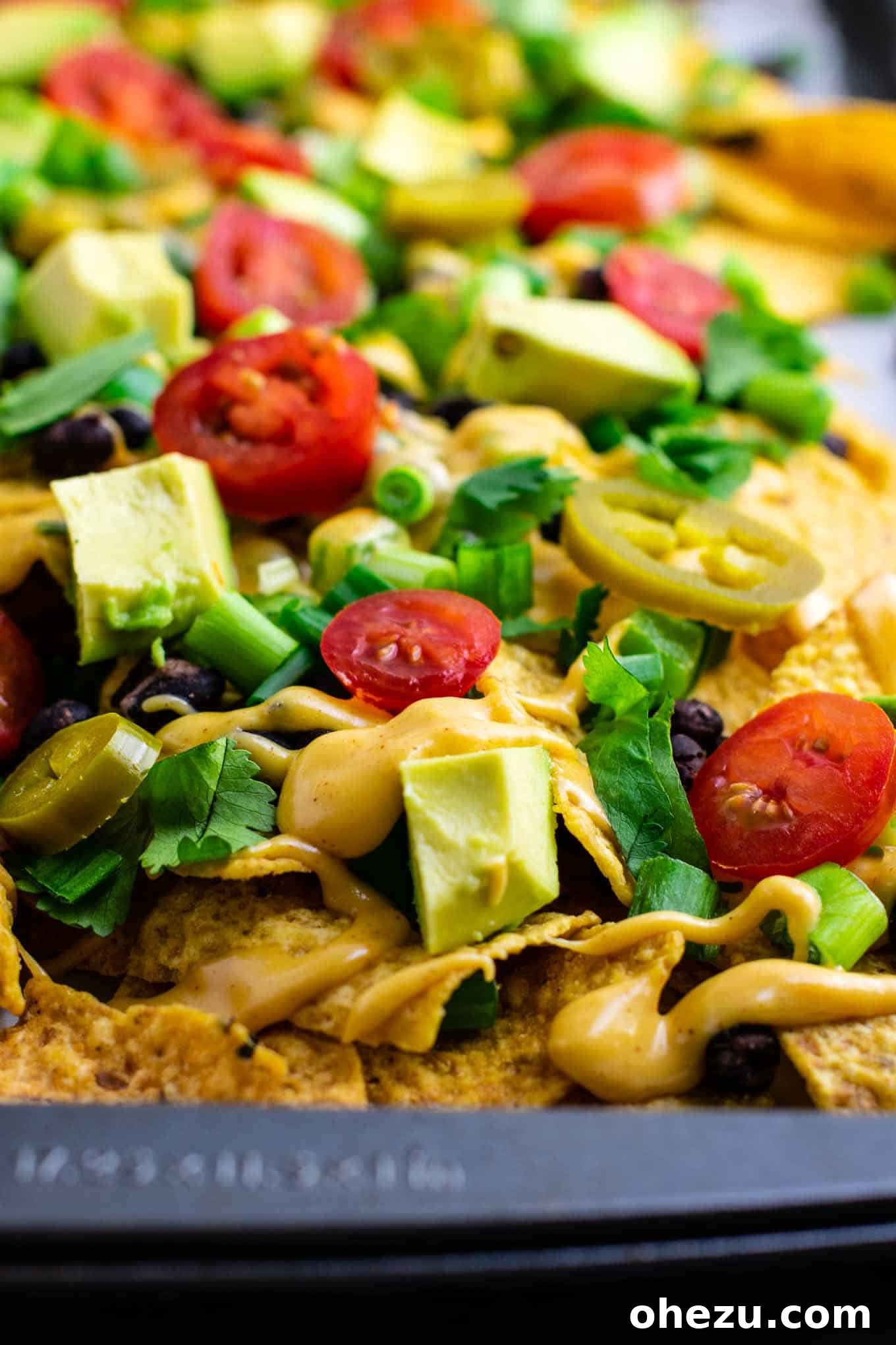 Ultimate Loaded Vegetable Nachos 5 Partially baked loaded veggie nachos with black beans and green bell peppers, ready for the cheese sauce. #veggienachos #vegetarian #nachocheese #nachocheesesauce