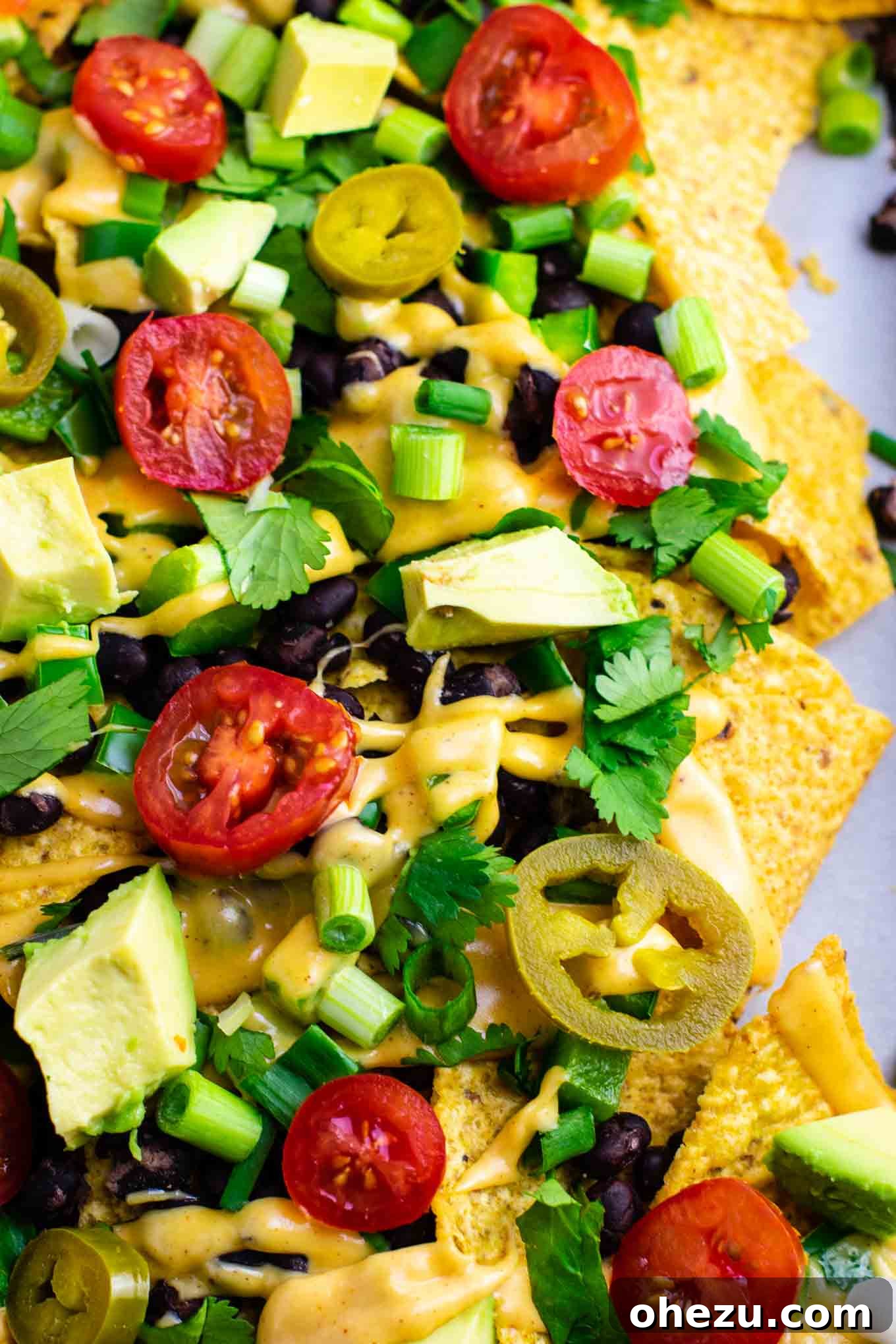 Ultimate Loaded Vegetable Nachos 6 The baked tortilla chips with beans and peppers, glistening and ready for the cheese sauce. #veggienachos #vegetarian #nachocheese #nachocheesesauce