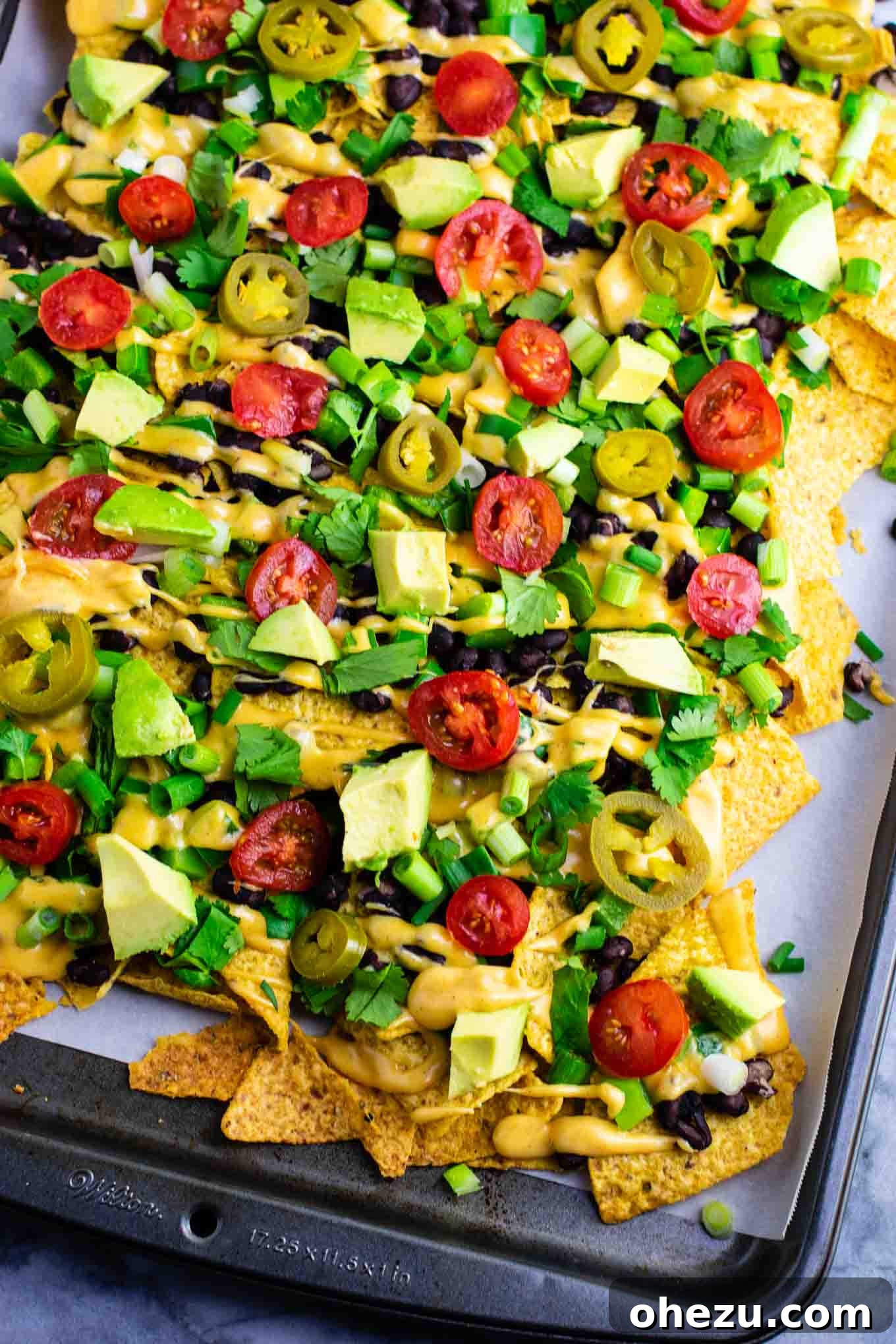 Ultimate Loaded Vegetable Nachos 7 A large platter of fully loaded veggie nachos, garnished and ready to be devoured. The perfect vegetarian party food! #veggienachos #vegetarian #nachocheese #nachocheesesauce