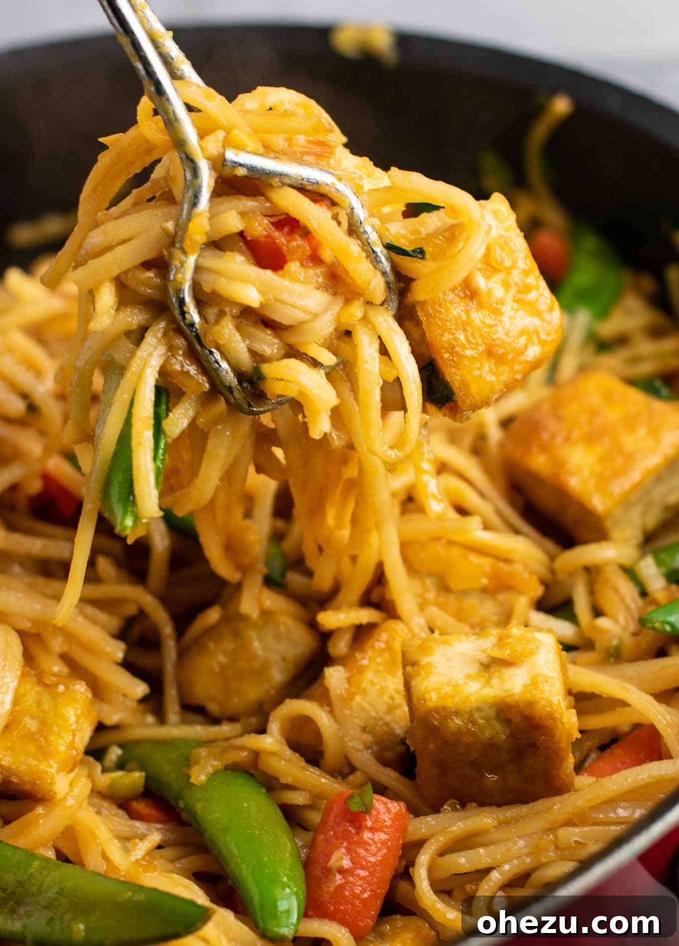 Gluten-free tofu noodle stir fry served in a bowl, garnished with fresh green onions.