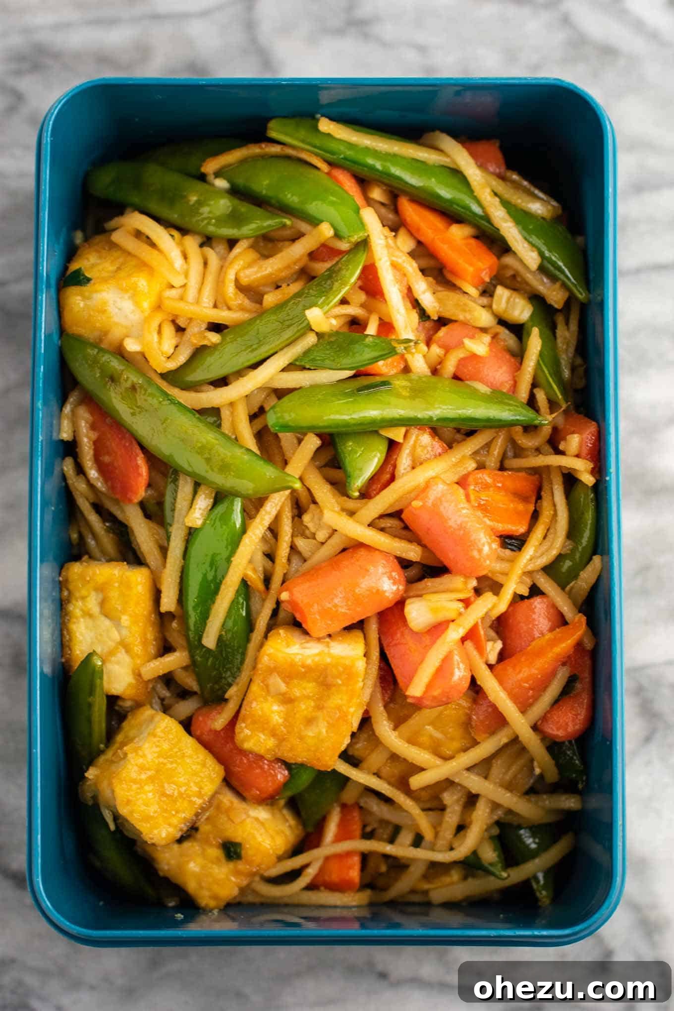 Multiple meal prep containers filled with tofu stir fry noodles, ready for the week.