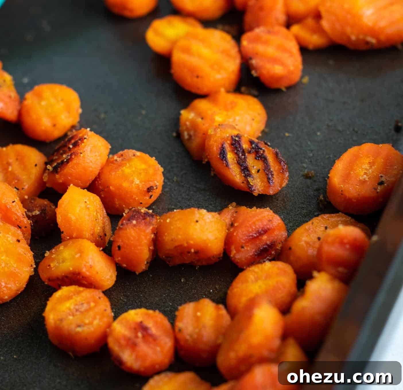 A baking sheet filled with raw frozen crinkle-cut carrots, coated in seasoning and ready for the oven.