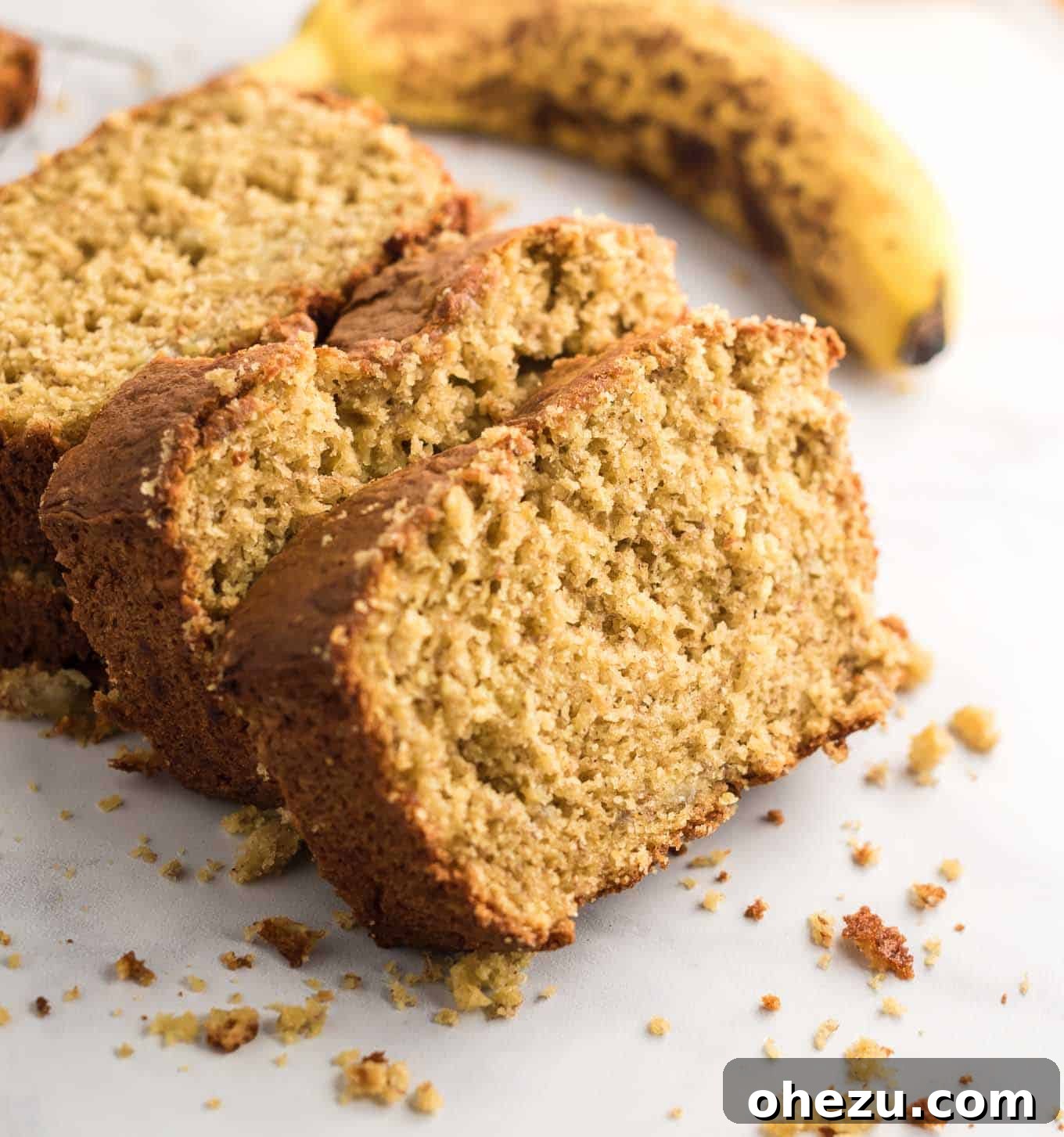banana bread sliced with a whole banana in the background, emphasizing its fresh ingredients