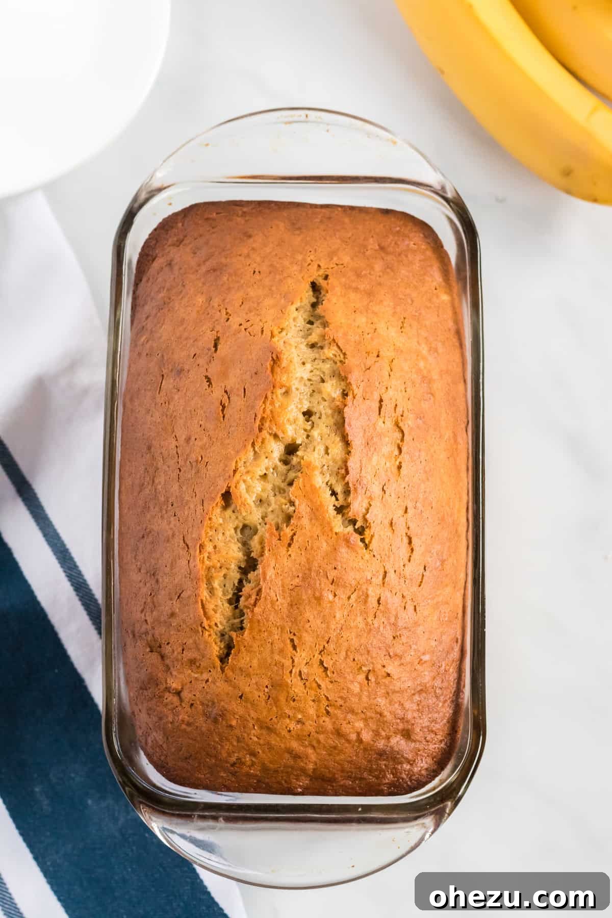 a freshly baked cake mix banana bread loaf cooling in a clear glass loaf pan
