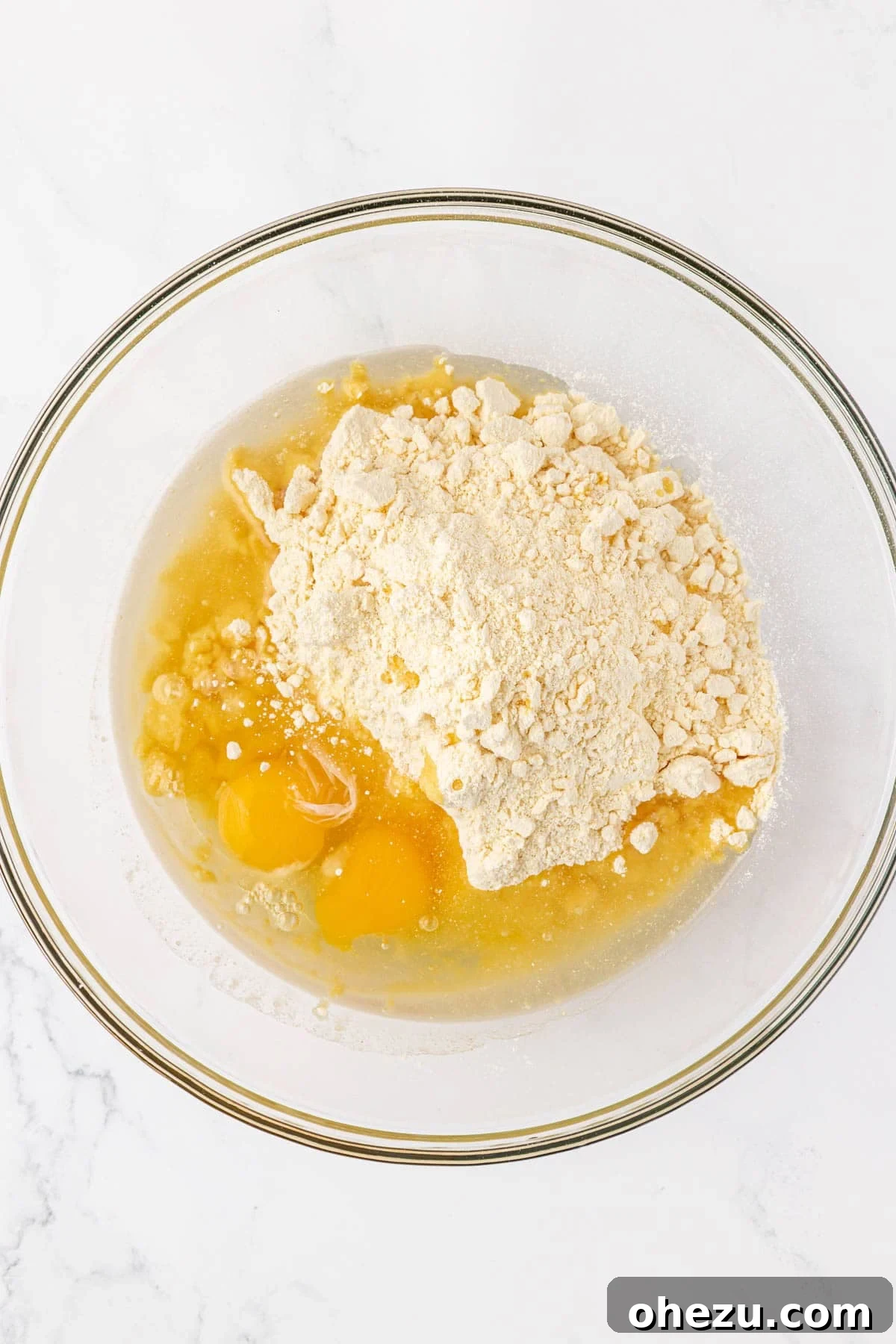 Yellow cake mix, eggs, and olive oil in a white mixing bowl before combining