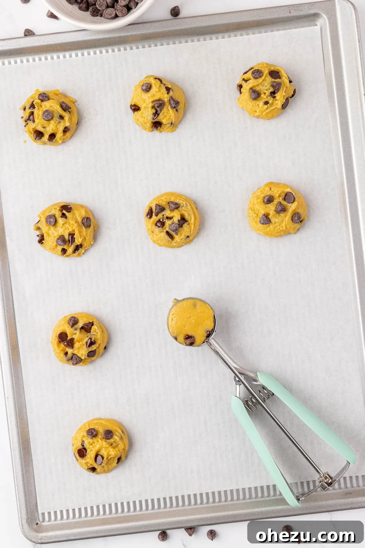 Raw cookie dough portions placed on a baking sheet lined with parchment paper