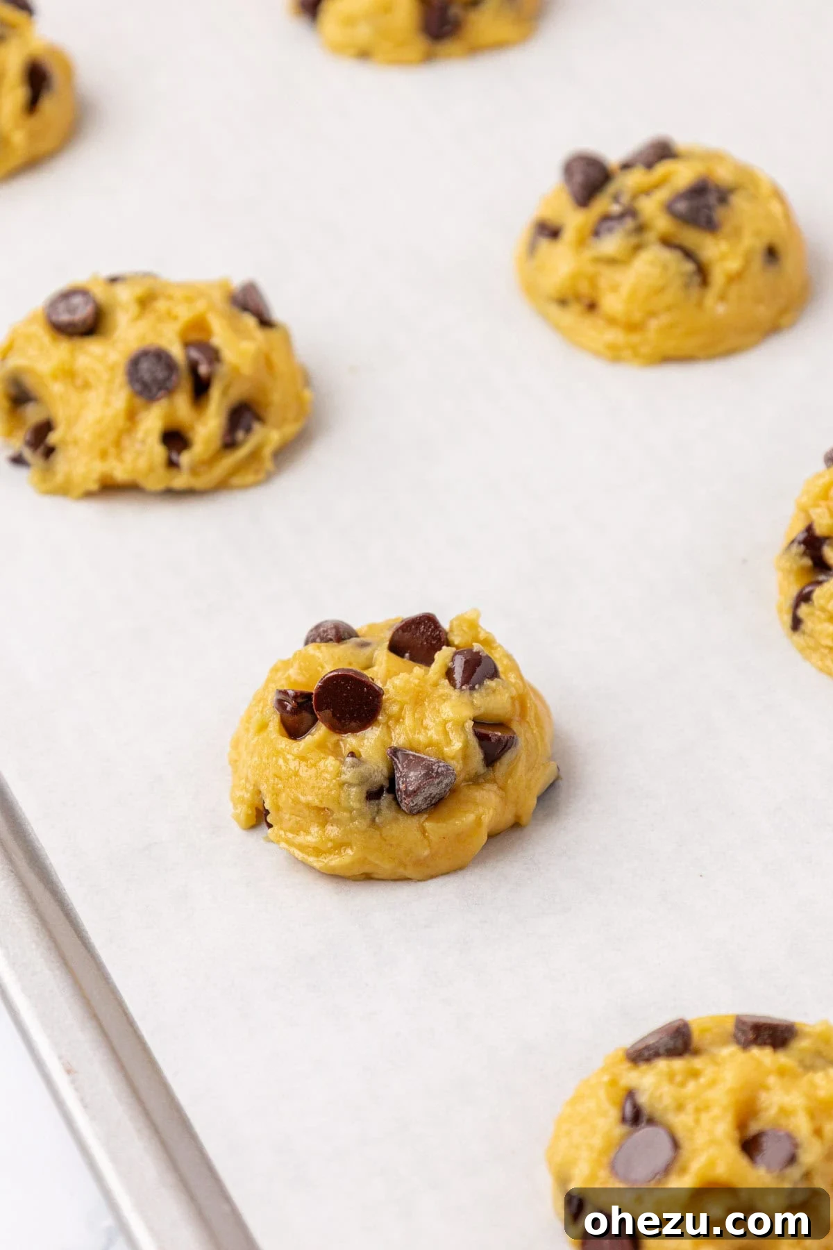 Close-up of cookie batter scooped onto a baking sheet, ready for the oven
