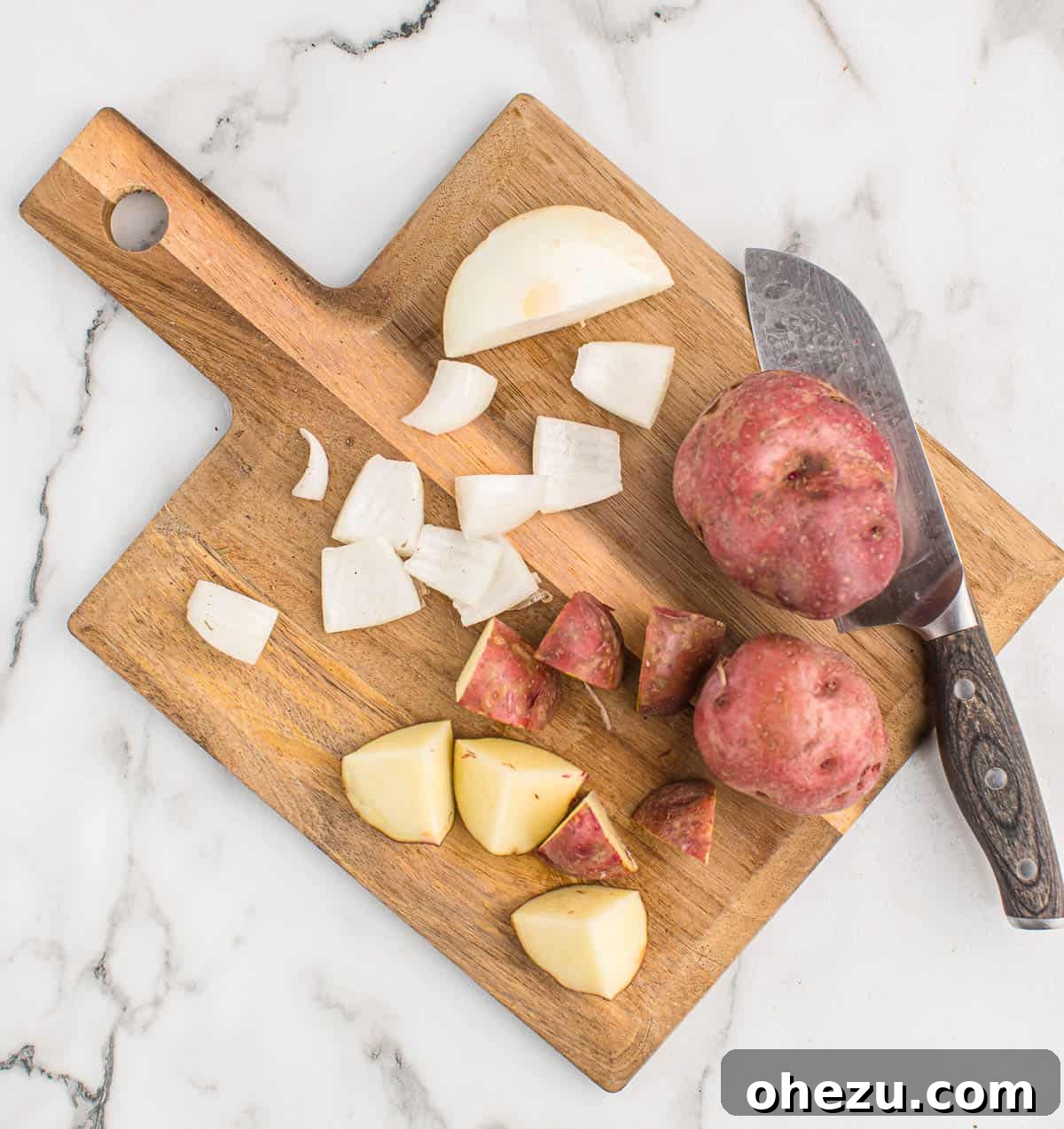 Cutting up red potatoes and onions on a wooden board