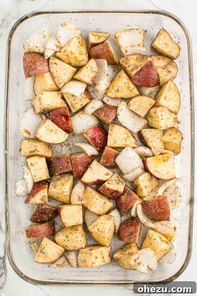 Roasted potatoes and onions halfway through baking in a dish