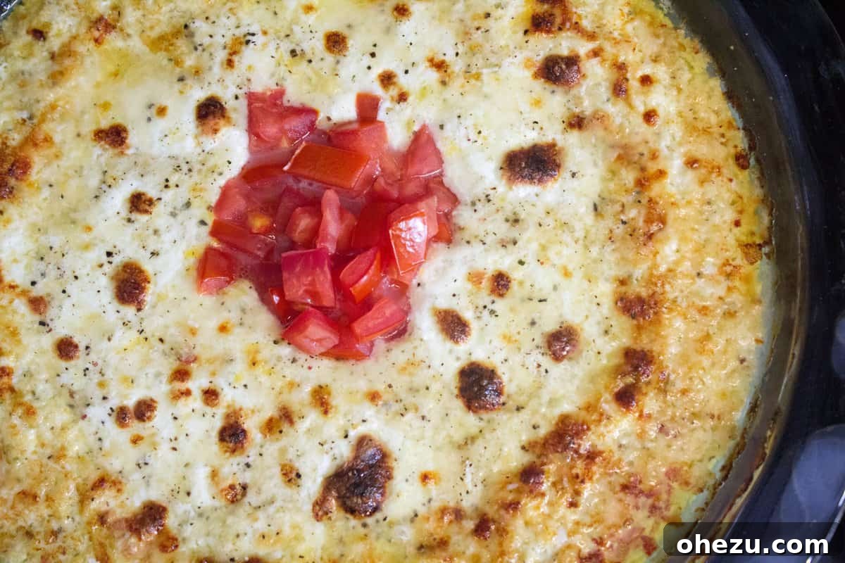 Close-up of golden-brown garlic cheese dip, showing its gooey texture, in a white ceramic dish