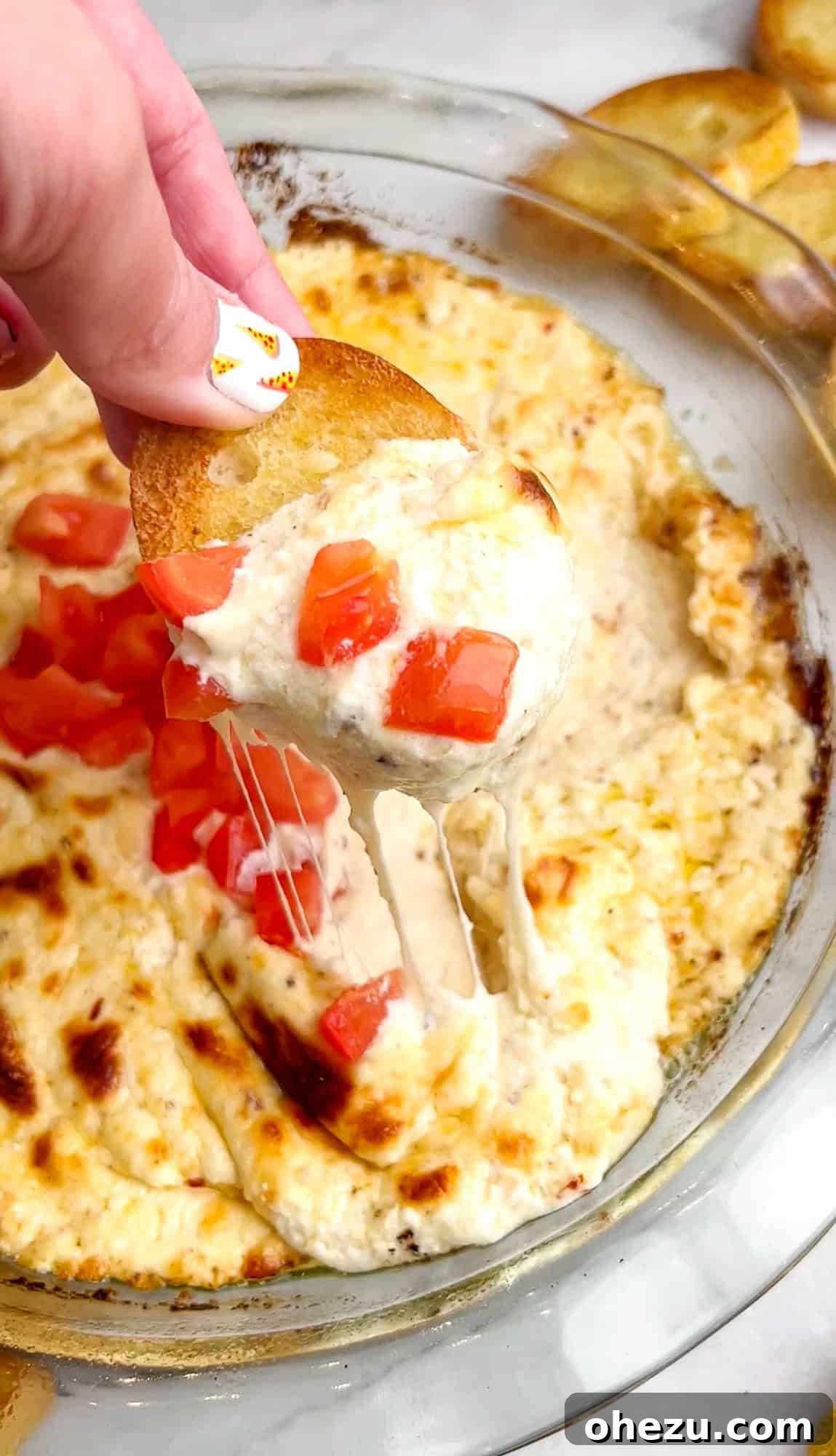 Close-up of a spoon scooping a generous portion of hot, bubbly garlic cheese dip, showcasing its gooey texture