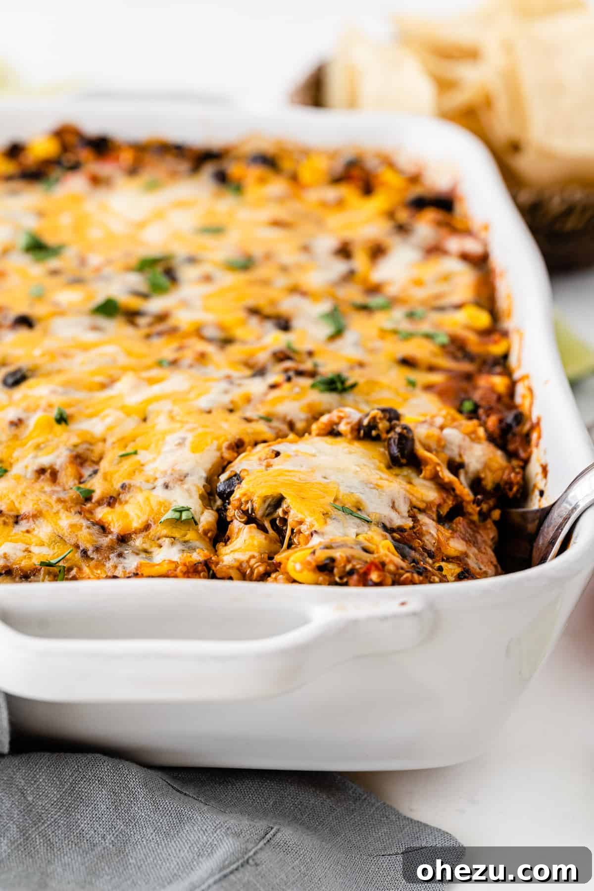 mexican quinoa casserole in a white baking dish with a spoon taking a scoop