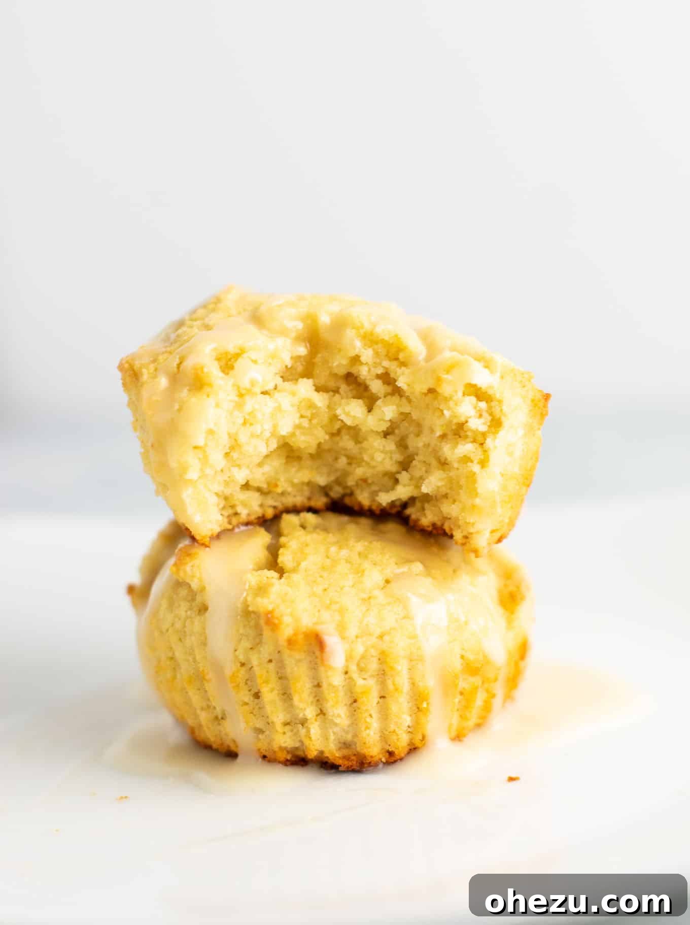A stack of delicious gluten-free lemon muffins with a generous drizzle of sweet lemon glaze, showcasing their soft texture and vibrant color.