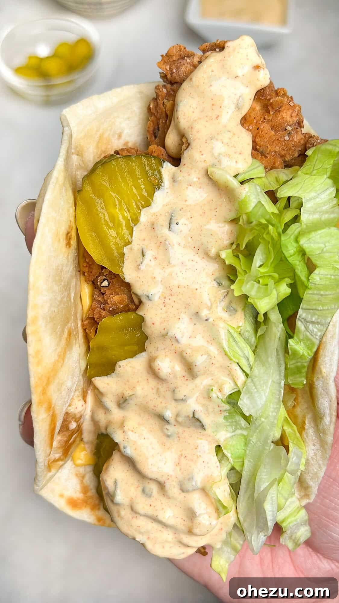 Ultimate Chicken Big Mac Taco 3 Close-up of a perfectly assembled fried chicken taco, rich with creamy Big Mac sauce, fresh shredded lettuce, and tangy pickles, held invitingly in a hand.