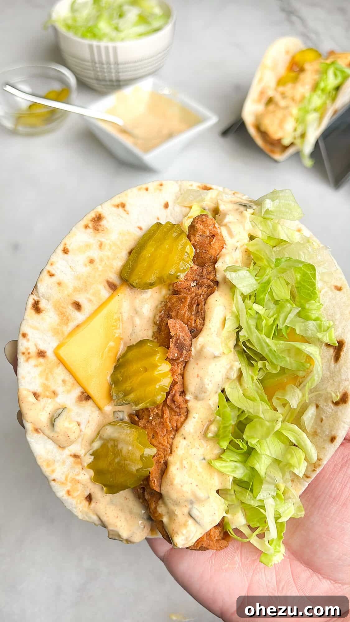 Ultimate Chicken Big Mac Taco 8 A close-up shot of a chicken Big Mac taco, open-faced, revealing its vibrant ingredients and homemade sauce, held in a hand.