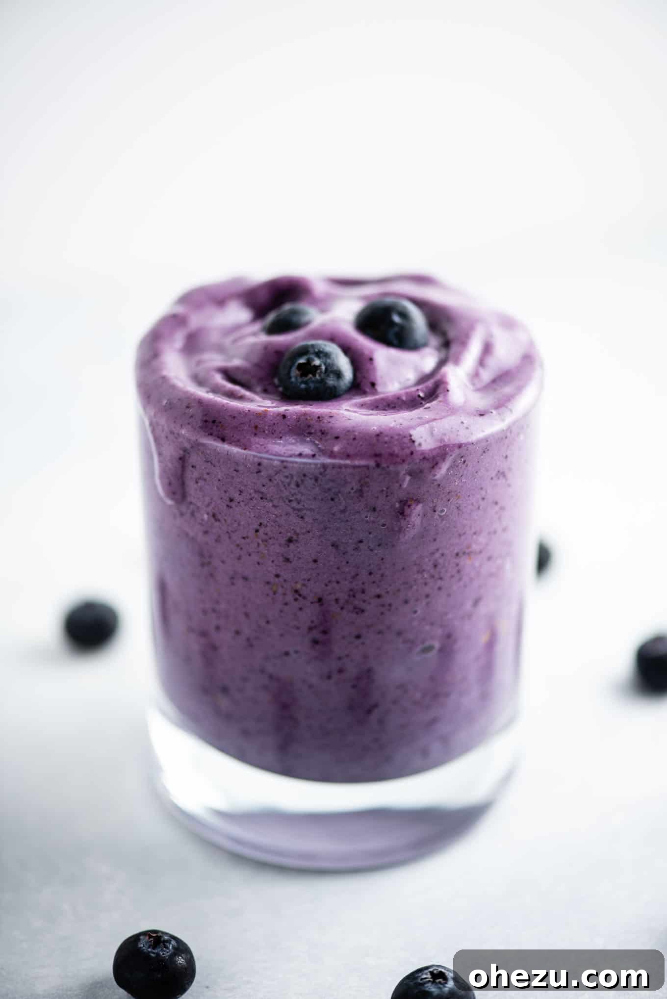 Velvet Berry Banana Smoothie 5 A tall glass filled with creamy blueberry banana smoothie, highlighting its inviting texture and the fresh fruit garnish.