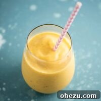 mango smoothie in a glass with a straw