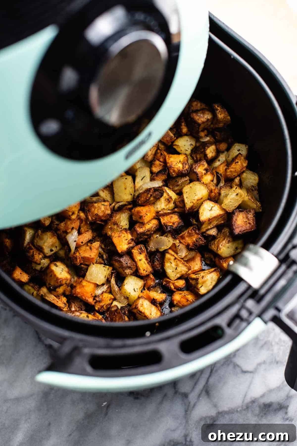 Crispy breakfast potatoes in an air fryer basket, ready to be served.