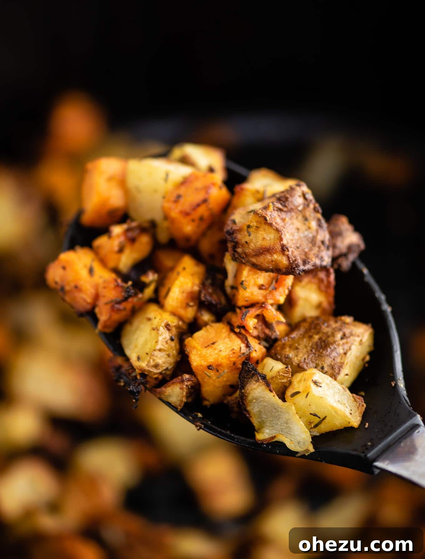Air fryer breakfast hash served on a black spoon, showcasing the mix of potatoes and onions.