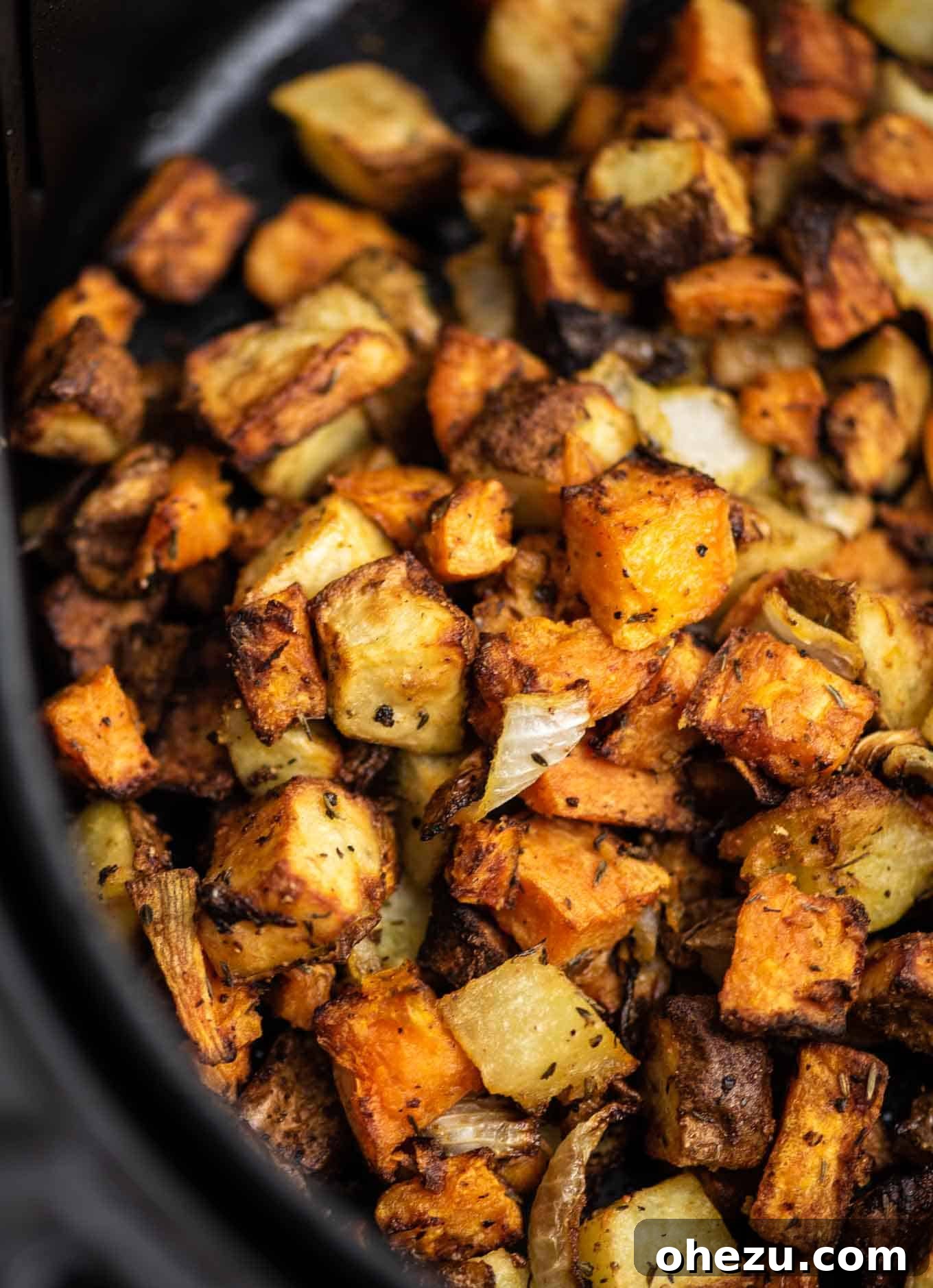 Overhead view of seasoned breakfast potatoes and onions ready to go into the air fryer.